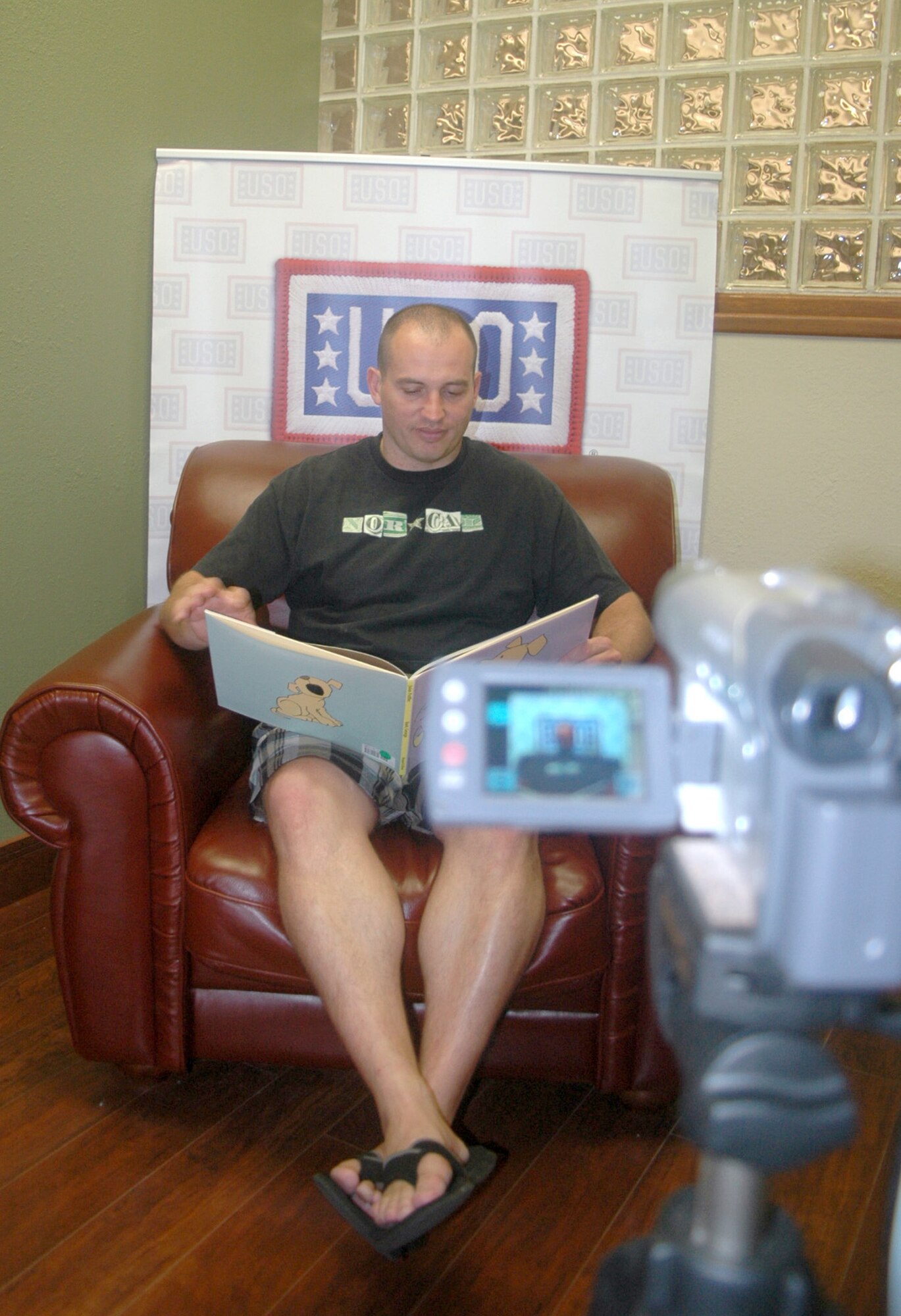 Tech. Sgt. David Aceveda reads a children's book in front of a video camera Sept. 24, 2010, inside the USO Community Center on Dover AFB, Del., as part of the United Through Reading program. While Sergeant Aceveda is deployed, the pre-recorded DVD and book will be sent to his children. Sergeant Aceveda is a member of the 744th Communications Squadron at Joint Base Andrews Naval Air Facility, Md. (U.S. Air Force photo/Tech. Sgt. Scott Farley) 