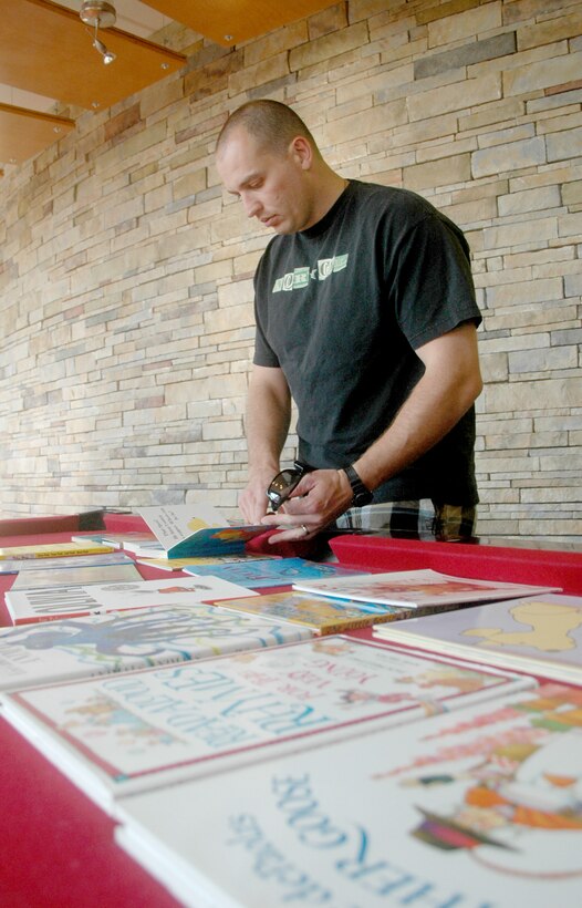 Tech. Sgt. David Aceveda sifts through books to read onto video Sept. 24, 2010, inside the USO Community Center on Dover AFB, Del., as part of the United Through Reading program. While Sergeant Aceveda is deployed, the pre-recorded DVD and book will be sent to his children. Sergeant Aceveda is a member of the 744th Communications Squadron at Joint Base Andrews Naval Air Facility, Md. (U.S. Air Force photo/Tech. Sgt. Scott Farley)