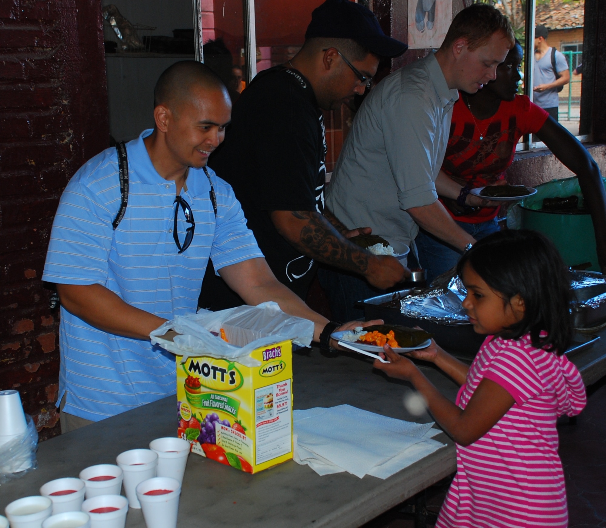 SOTO CANO AIR BASE, Honduras - U.S. Navy MA2 Kenneth Decena serves dinner to a child from the Hogar Tierra Santa Orphanage, Sunday, 14 Nov 2010.  20 members of the Joint Task Force-Bravo team visited the children to serve them dinner, bring clothing and participate in games and laughter.  The orphanage is just one of several that are sponsored by members of JTF-B. (U.S. Air Force photo/Capt. John T. Stamm)