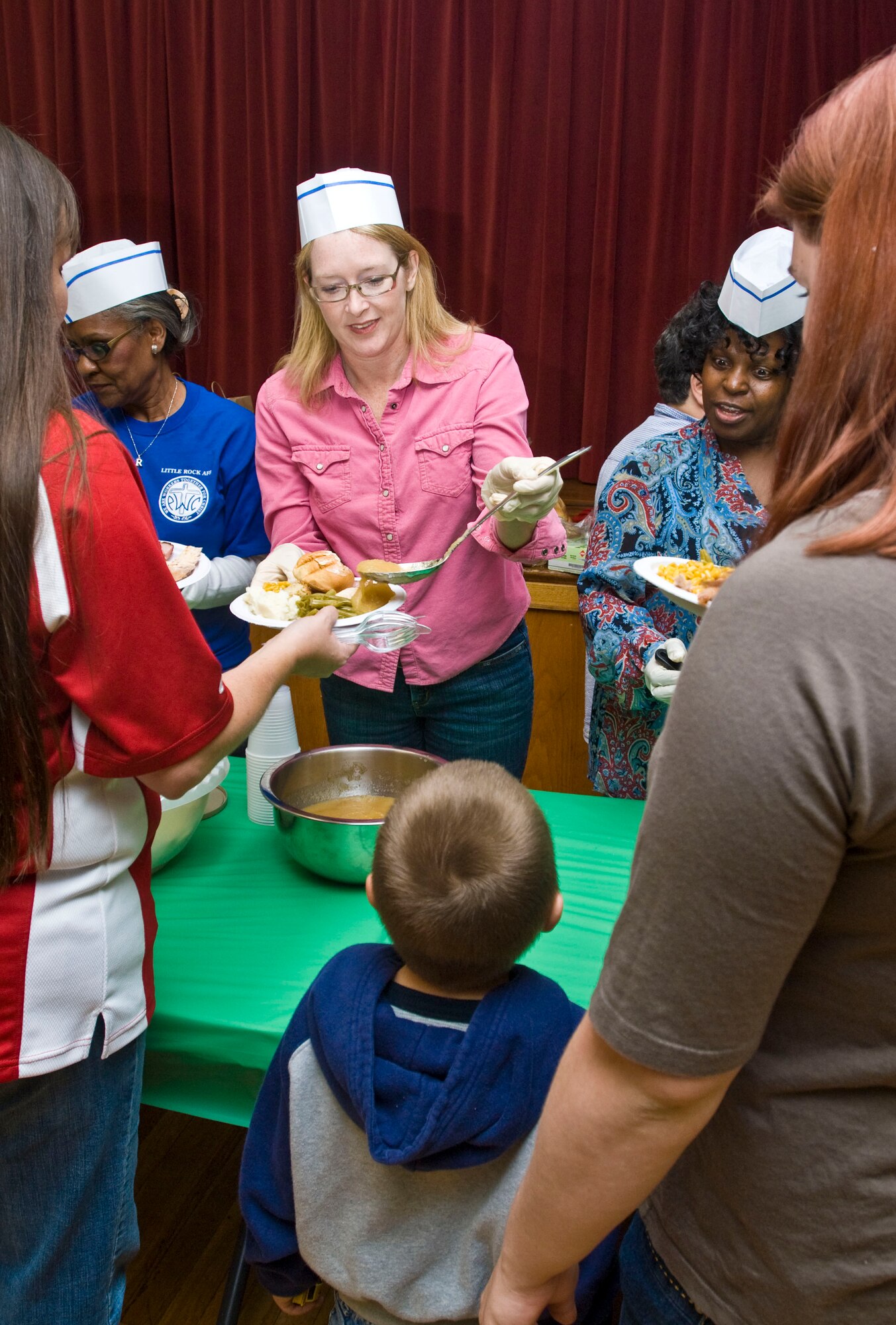 Ashley Minihan (center), wife of the 19th Airlift Wing commander, Col. Mike Minihan, serves applesauce during the deployed family dinner Nov. 9, 2010, at the Thomas Community Activities Center at Little Rock Air Force Base, Ark. The chapel-sponsored event was held for families of deployed Airmen. (U.S. Air Force photo by Staff Sgt. Nestor Cruz)
