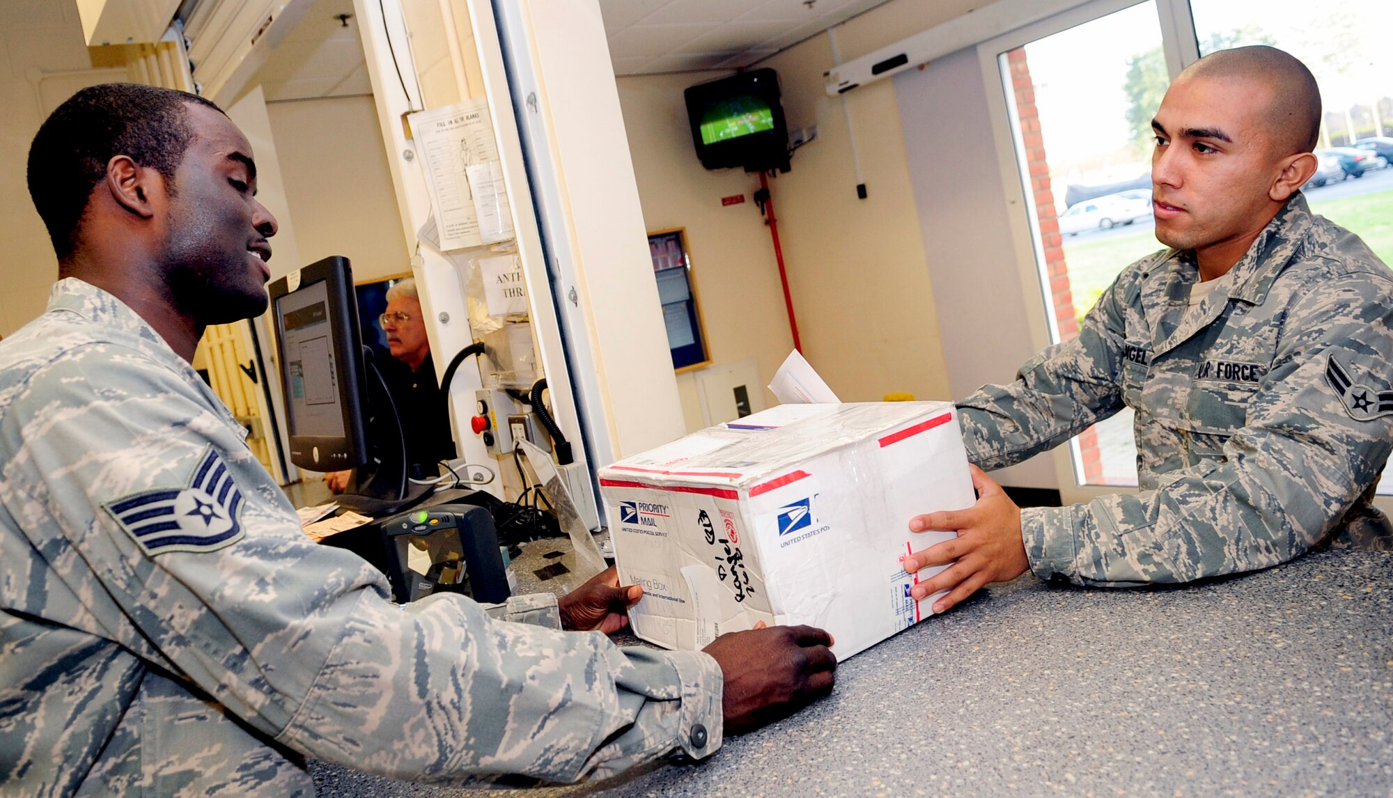 RAF MILDENHALL, England -- Staff Sgt. Dustin Hicks, 100th Communications Squadron postal specialist, passes Airman 1st Class Rosendo Rangel, 100th Logistics Readiness Squadron, his parcel at the base post office Nov. 15, 2010. The post office has holiday shipment deadlines of Nov. 26 for standard parcel post, Dec. 10 for priority and first class, and Dec. 17 for express mail. (U.S. Air Force photo/Senior Airman Ethan Morgan)