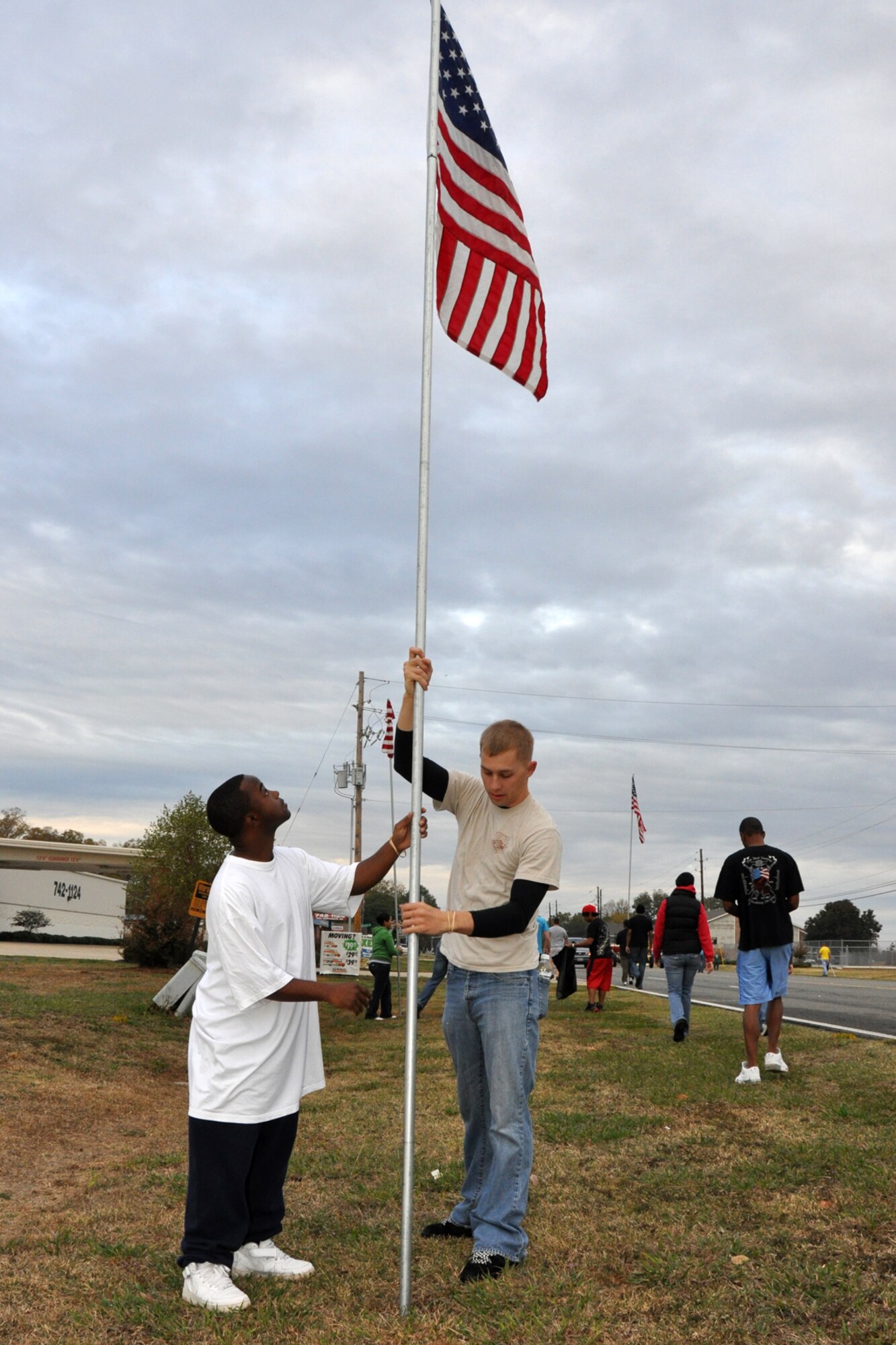Staff Sgt. (S) Darrell Cross-Williams, non-destructive inspection maintenance, 2nd Maintenance Squadron, and Staff Sgt. (S) Joseph Romaine, client systems, 2nd Communications Squadron, put up an America Flag along North Gate Road outside Barksdale Air Force Base, La., Nov. 11, 2010. The flags lined the road for approximately a half mile from the North Gate to Patricia Drive, and were removed approximately 11 hours later, at the end of the day. The Airmen were among approximately 57 Barksdale Airmen who posted American Flags along North Gate Road and Barksdale Air Force Base Boulevard to commemorate Veteran's Day at Barksdale. (U.S. Air Force photo/Tech. Sgt. Jeff Walston)
