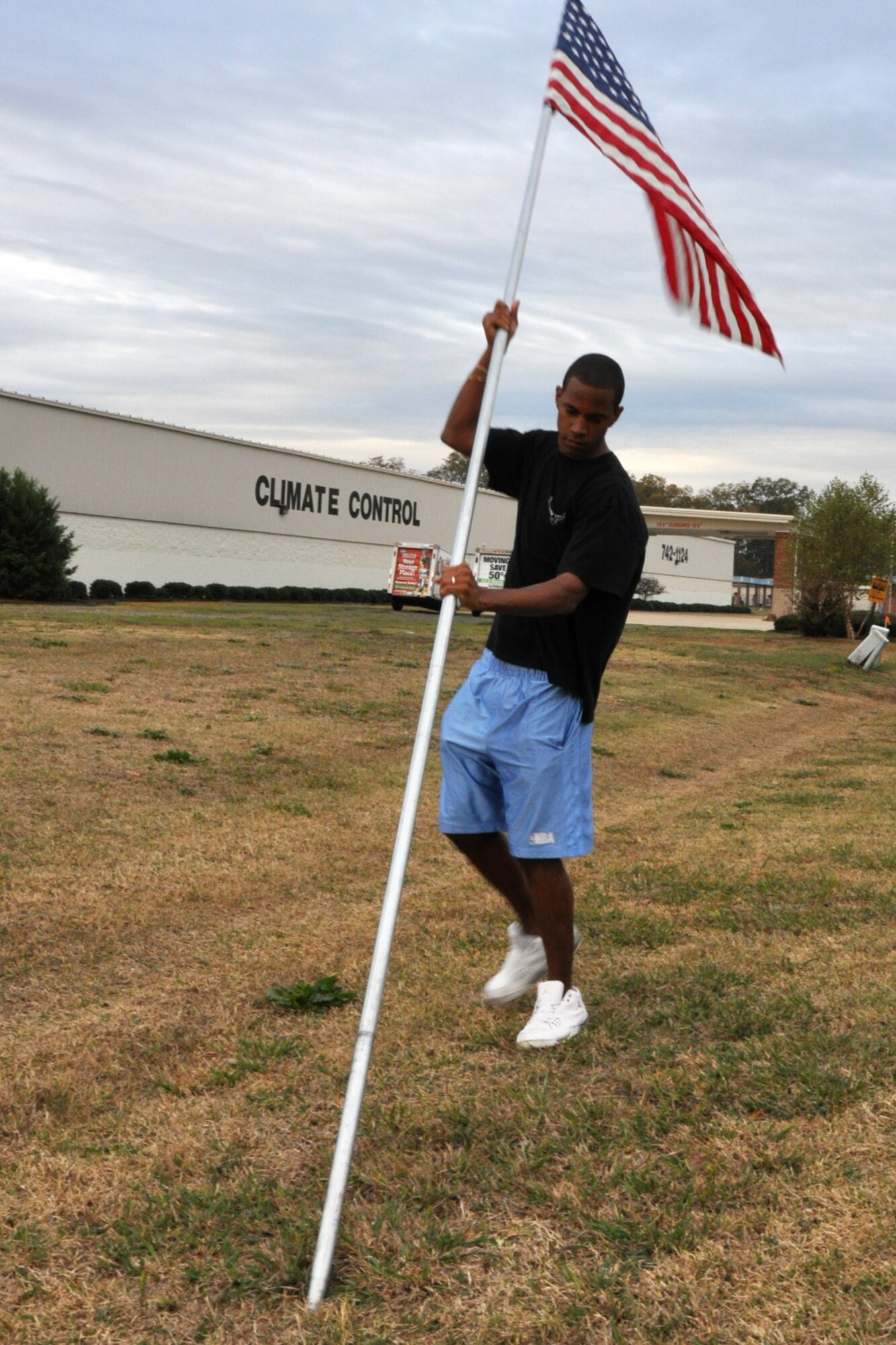 Airman First Class Jeffery Hairston, a contracting specialist with the 2nd Bomb Wing Contracting Squadron, puts up an America Flag along North Gate Road outside Barksdale Air Force Base, La., Nov. 11, 2010. The flags lined the road for approximately a half mile from the North Gate to Patricia Drive, and were removed approximately 11 hours later, at the end of the day. (U.S. Air Force photo/Tech. Sgt. Jeff Walston)