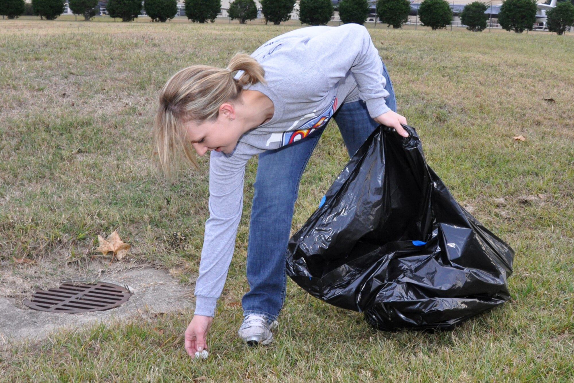 Staff Sgt. Pamela Goolsby, executive assistant to the command surgeon, Air Force Global Strike Command, picks up trash along North Gate Road outside Barksdale Air Force Base, La., Nov. 11, 2010. Sergeant Goolsby was one of approximately 40 Airmen who volunteered to post American Flags and pick up trash along the road in commemoration of Veteran's Day. The flags lined the road for approximately a half mile from the North Gate to Patricia Drive, and were removed approximately 11 hours later, at the end of the day. (U.S. Air Force photo/Tech. Sgt. Jeff Walston)