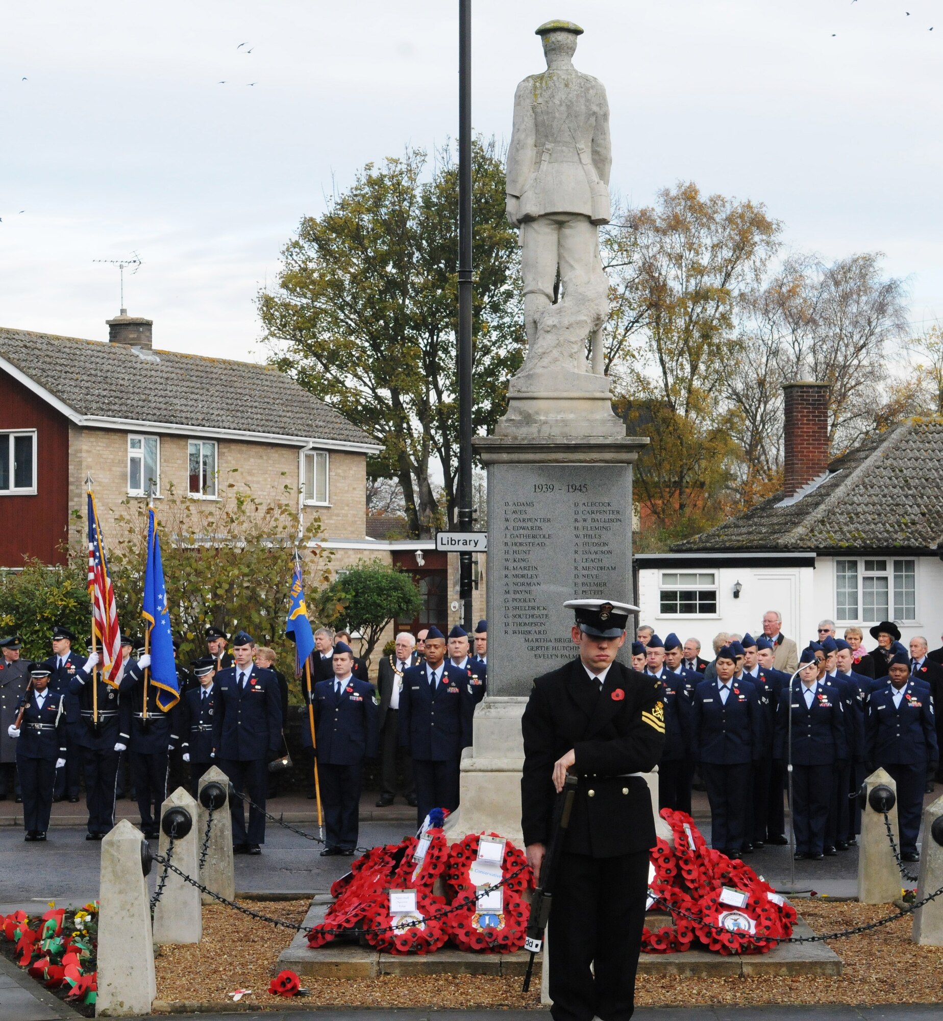 RAF MILDENHALL, England -- A representative of Training Ship Fox, Sea Cadet Corps, stands guard at the Mildenhall war memorial while an honor guard and marching contingent from RAF Mildenhall stand in formation during a remembrance service Nov. 14, 2010. Remembrance Sunday is a British observance held on the second Sunday in November to remember the men and women who have died in combat. (U.S. Air Force photo/Staff Sgt. Thomas Trower)