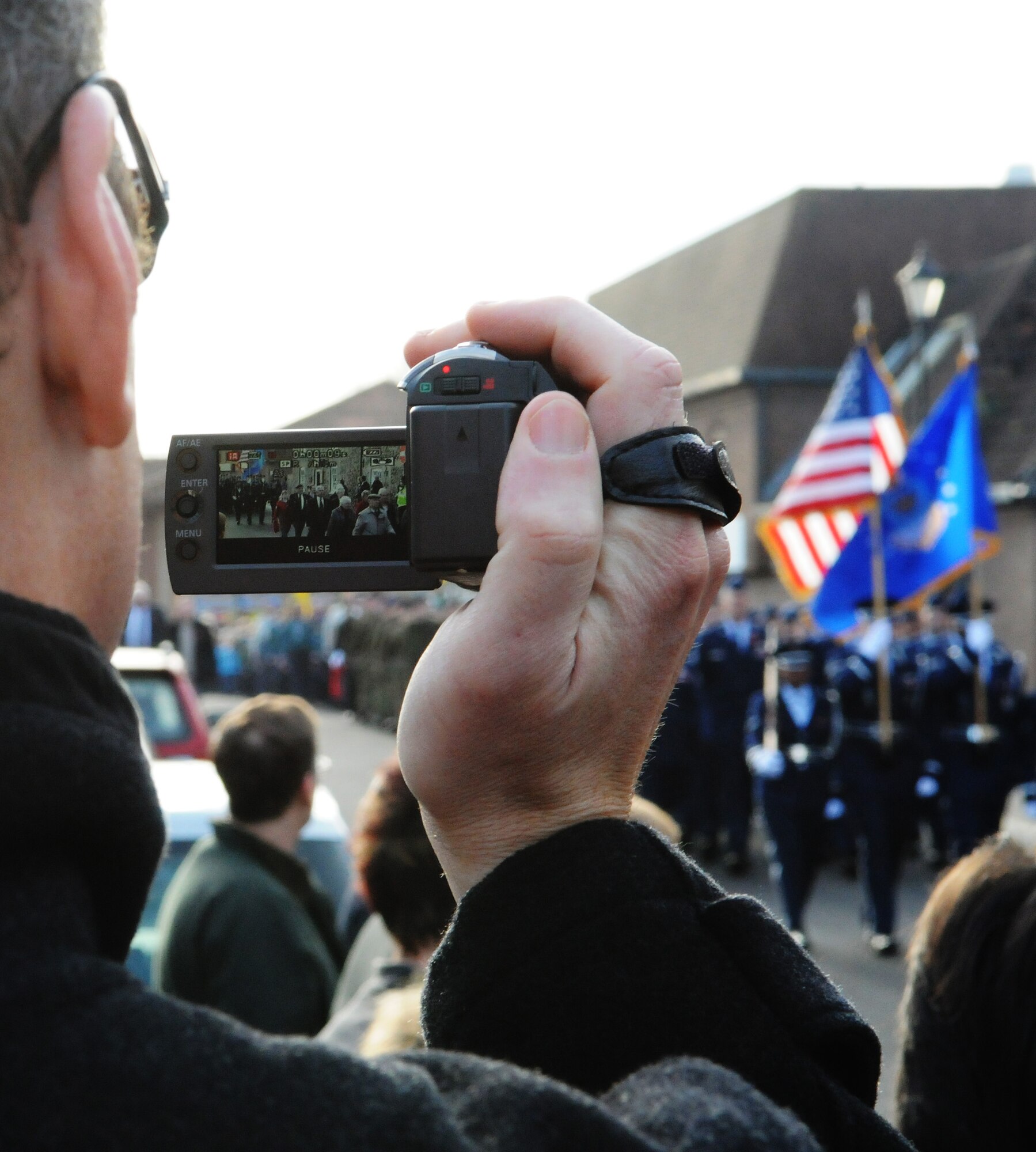 RAF MILDENHALL, England -- A Mildenhall townsman records the honor guard and marching contingent from RAF Mildenhall during a Remembrance Sunday ceremony in the town center Nov. 14, 2010. Leaders from organizations across the area participated in the ceremony by placing remembrance wreaths at the base of the town's war memorial. Remembrance Day, the British equivalent of Veterans Day, is observed annually on Nov. 11, the anniversary of when World War II hostilities ended on the 11th hour of the 11th day of the 11th month. (U.S. Air Force photo/Staff Sgt. Thomas Trower)