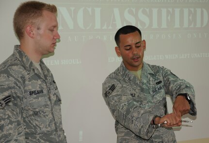 SOTO CANO AIR BASE, Honduras --  Senior Airman Erich Spielmaker, left, of the 612th Air Base Squadron, gets a lesson in how to hold handcuffs while apprehending a suspect from Senior Airman Jaime Perez, of the Joint Security Forces, during a recent JSF augmentee training class here. Maintaining contral over the handcuffs is important to both the safety of everyone involved. (U.S. Air Force photo/Tech. Sgt. Benjamin Rojek)