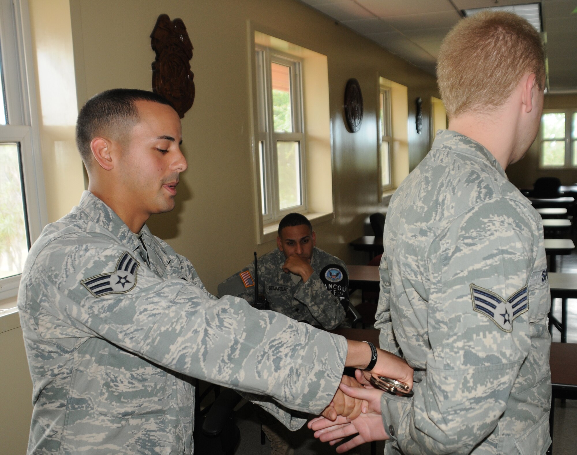 SOTO CANO AIR BASE, Honduras --  Senior Airman Jaime Perez, left, of the Joint Security Forces here, handcuffs Senior Airman Erich Spielmaker, of the 612th Air Base Squadron, during JSF augmentee training here recently. The training course covered such topics as apprehension and vehicle search techniques. (U.S. Air Force photo/Tech. Sgt. Benjamin Rojek)