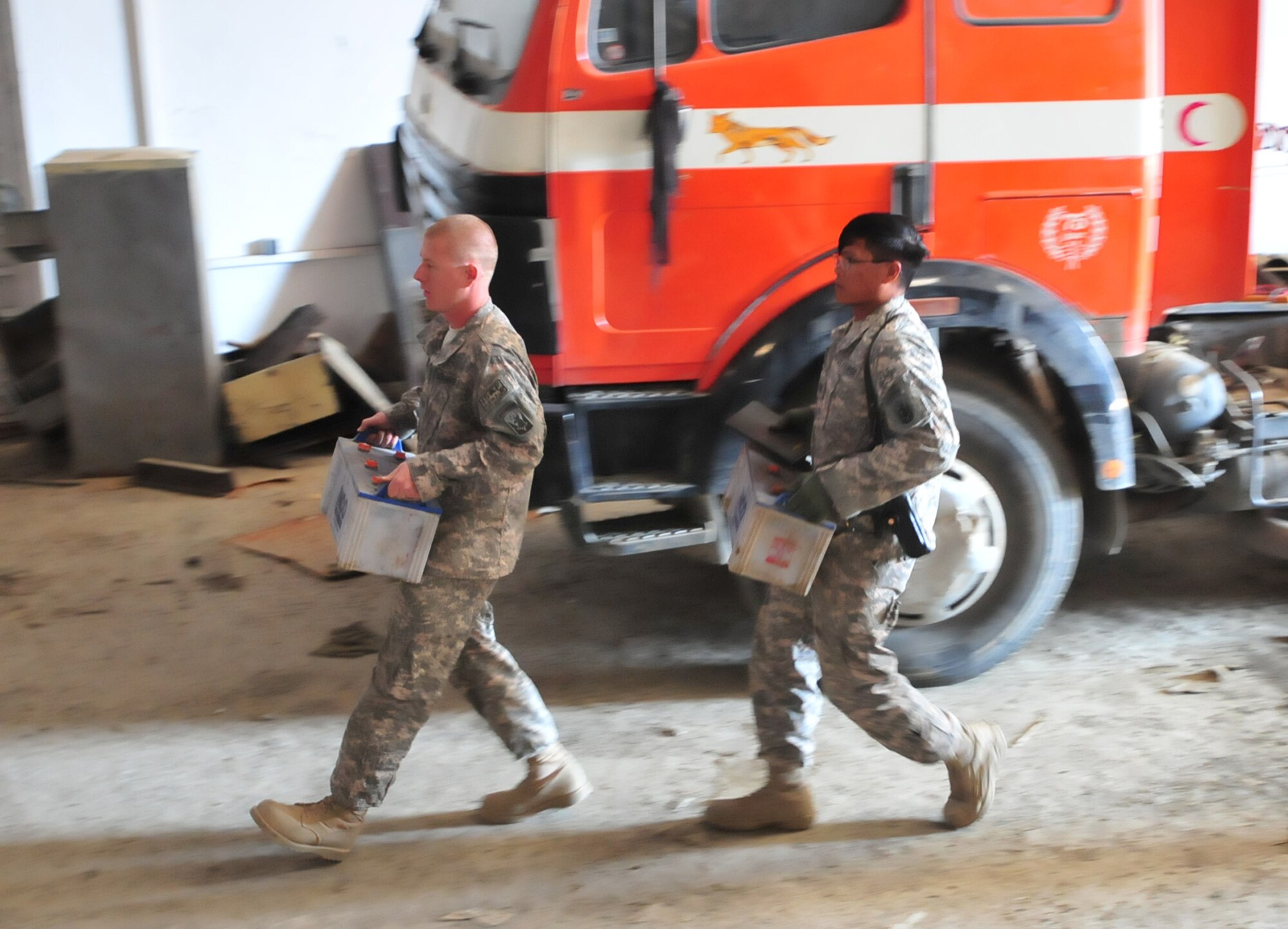 PANJSHIR PROVINCE, Afghanistan ? U.S. Air Force Tech. Sgt. Raymond Ibay, Panjshir Provincial Reconstruction Team vehicle management superintendent and Jacksonville Beach, Fla., native, and U.S. Air Force Staff Sgt. Michael Lamonte, Panjshir PRT vehicle maintenance lead mechanic and Burlington, Conn., native, carry two heavy-equipment batteries prior to performing a preventative maintenance inspection on Panjshir Department of Public Works? snow-removal equipment.  Sergeants Ibay and Lamonte, experienced vehicle and heavy-equipment mechanics, offer their skills to identify maintenance issues before Panjshir?s first snowfall.  (U.S. Air Force Photo by Tech. Sgt. Sean Mateo White, Panjshir Provincial Reconstruction Team Photographer)
