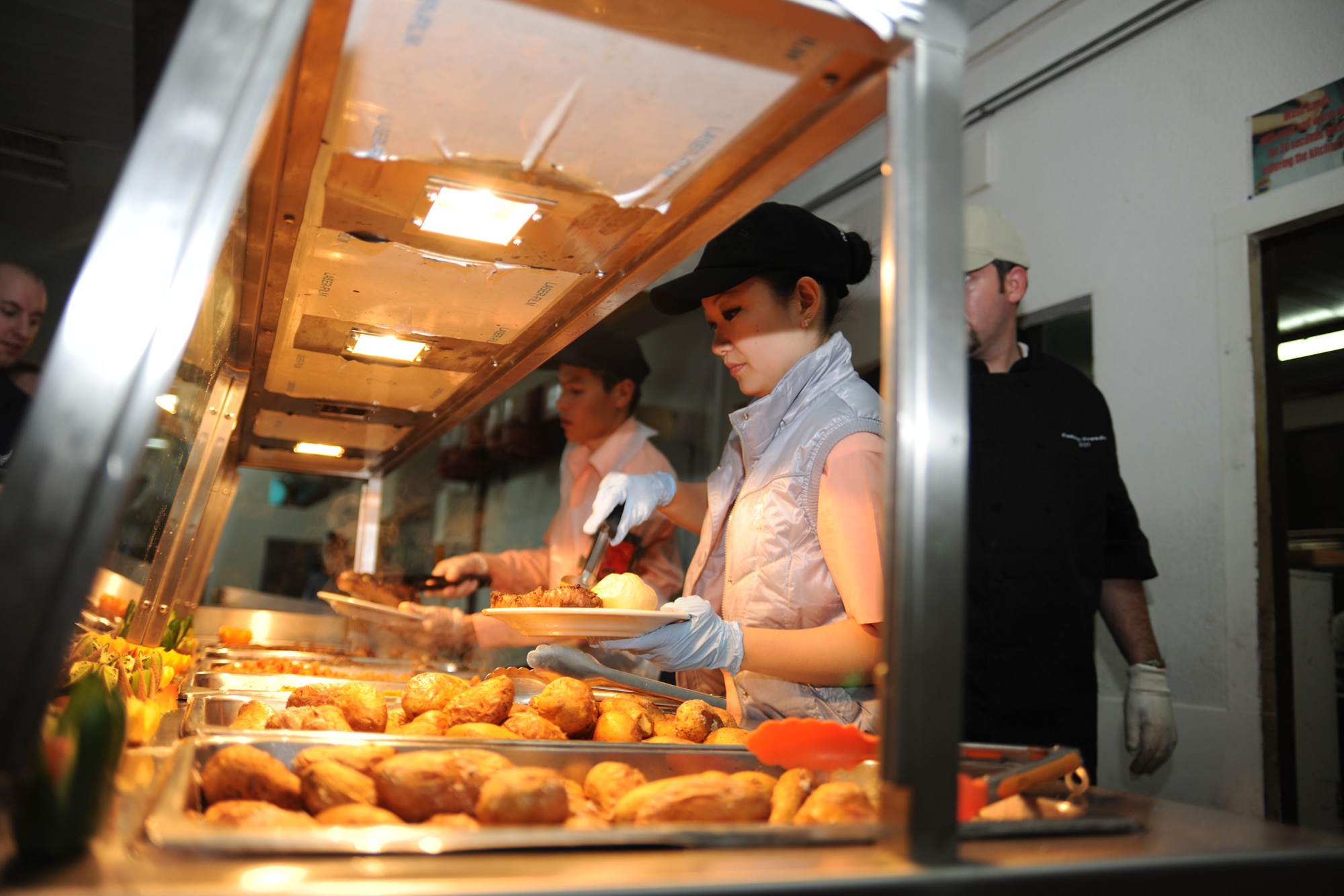 TRANSIT CENTER AT MANAS, Kyrgyzstan - Dining Facility workers serve food prepared by Outback Steakhouse Incorporated (OSI) employees during an Armed Forces Entertainment tour to the Transit Center at Manas Nov. 11.  OSI owns Outback Steakhouse, Carrabba's Italian Grill, Bonefish Grill, Fleming's Prime Steakhouse and Wine Bar and Roy's Hawaiian Fusion Cuisine.  Employees volunteered to visit with the troops and prepared 4,400 meals here in celebration of Veterans Day.   (U.S. Air Force photo/Staff Sgt. Michael Schocker)