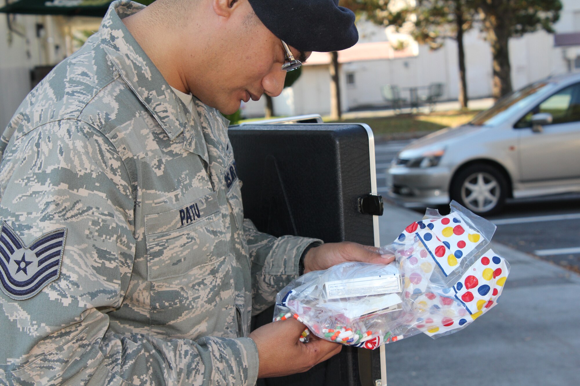 YOKOTA AIR BASE, Japan -- Tech. Sgt. Happyvalley Patu, 374th Security Forces Squadron, examines a bag of pills dropped off at the East Shoppette Nov. 10. The pills were discarded as part of a medication drop-off event sponsored by the Drug Demand Reduction Program in conjunction with base law enforcement agencies. The event kicked off the Lock Your Meds campaign, which aims to encourage people to safeguard medications and properly discard any that are no longer needed. (U.S. Air Force photo submission/Sequoiya Lawson)