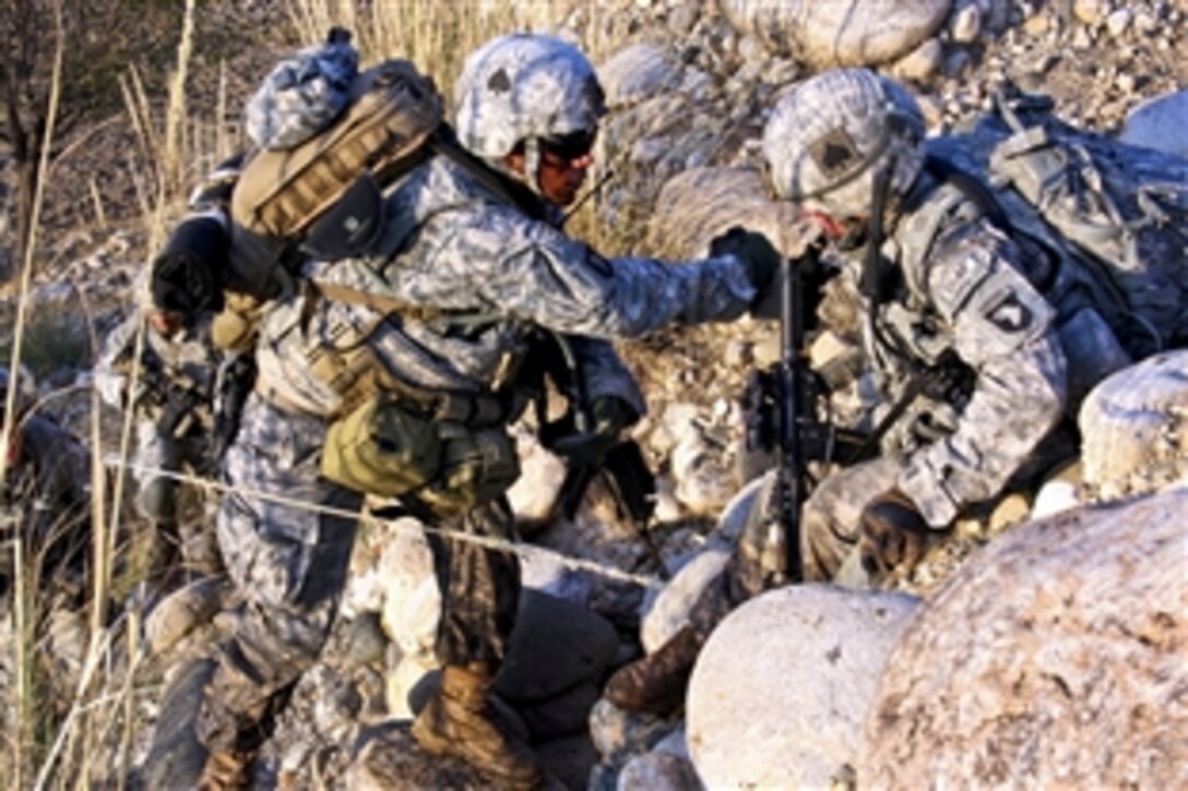 U.S. Army Sgt. James Small, right, helps Spc. Andreas Plaza up a mountainside in the Towr Gahr Pass, Nangarhar province, Afghanistan, Nov. 6, 2010. Small and Plaza are assigned to 1st Squadron, 61st Cavalry Regiment.