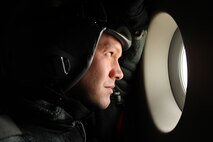 Staff Sgt. Jason Jones, 535th Airlift Squadron loadmaster, looks out over the mountainous terrain of the Pacific Northwest during a training mission Nov. 13 at Joint Base Lewis-McChord. The 535th AS aircrew trained in unrestricted descent assault landings, air drop, combat offloads, air refueling, night vision goggle training, combat offloads, low levels, mountainous terrain, assault landings, threat responses and multiple ship formation training during a five day training trip to Washington Nov 12-17. (U.S. Air Force photo/Staff Sgt. Mike Meares)