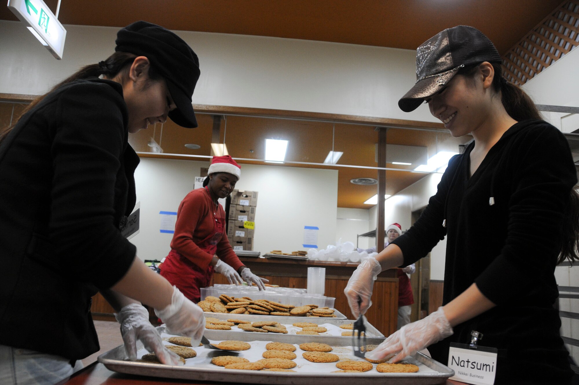Ms. Sariko Ishigaki and Ms. Natsumi Kitagawa prepare the cookies for packing while Ms. Pat Davis, spouse of Chief Master Sgt. James Davis, 18th Wing commander chief, prepares the packaging tin at Kadena Air Base Nov. 16. The local community assisted in making 2,500 packages of cookies that will be delivered to all military dorm residents. (U.S. Air Force photo/Staff Sgt. Darnell T. Cannady)