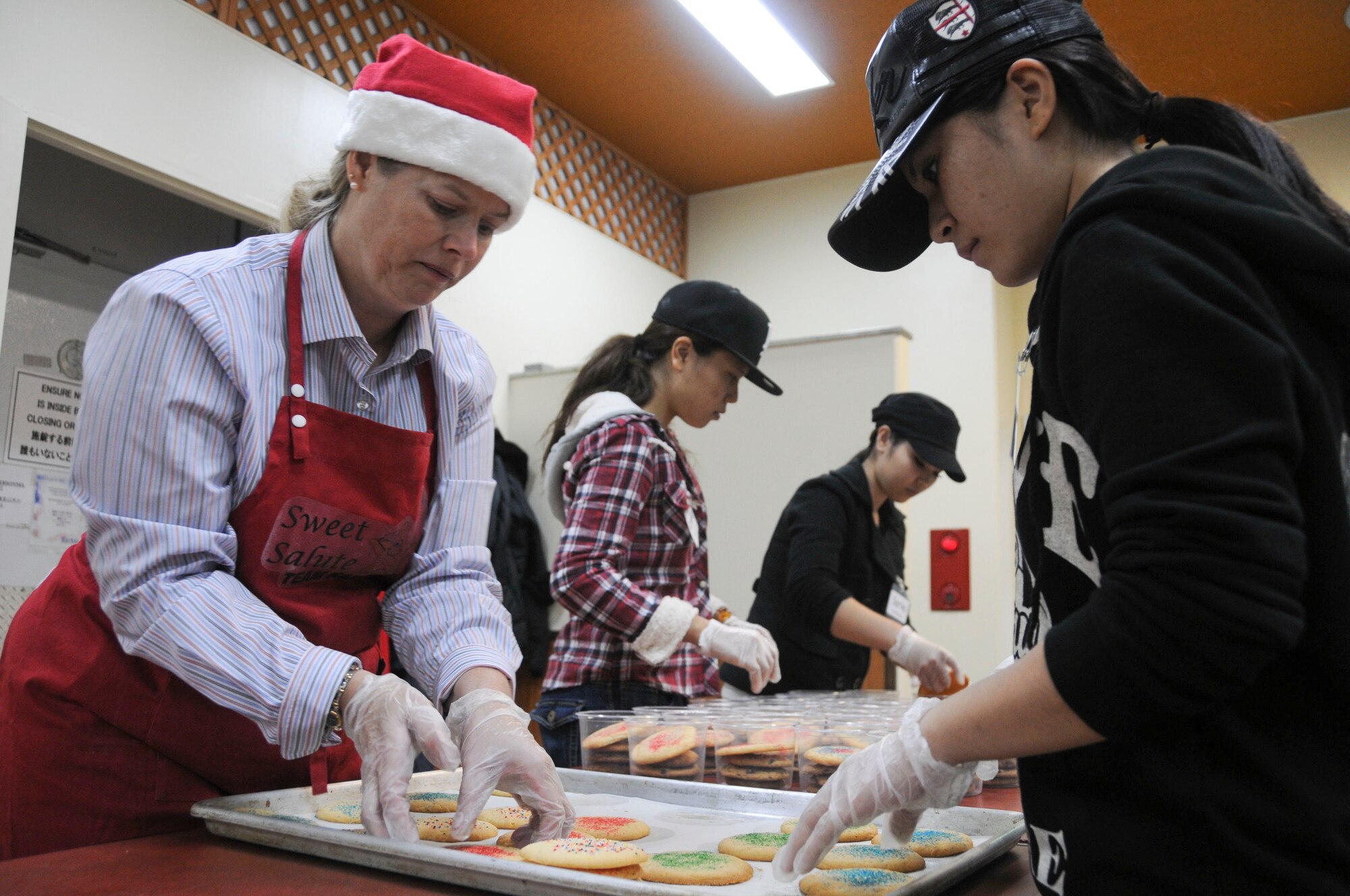 Ms. Charlotte Rupp, wife of 18th Wing Vice Commander Col. Ricky Rupp, assists Ms. Marumi Furukawa and other volunteers from the local community with preparing cookies to be packaged at Kadena Air Base Nov. 16. The local community assisted in making 2,500 packages of cookies for all military dorm residents. (U.S. Air Force photo/Staff Sgt. Darnell T. Cannady)
