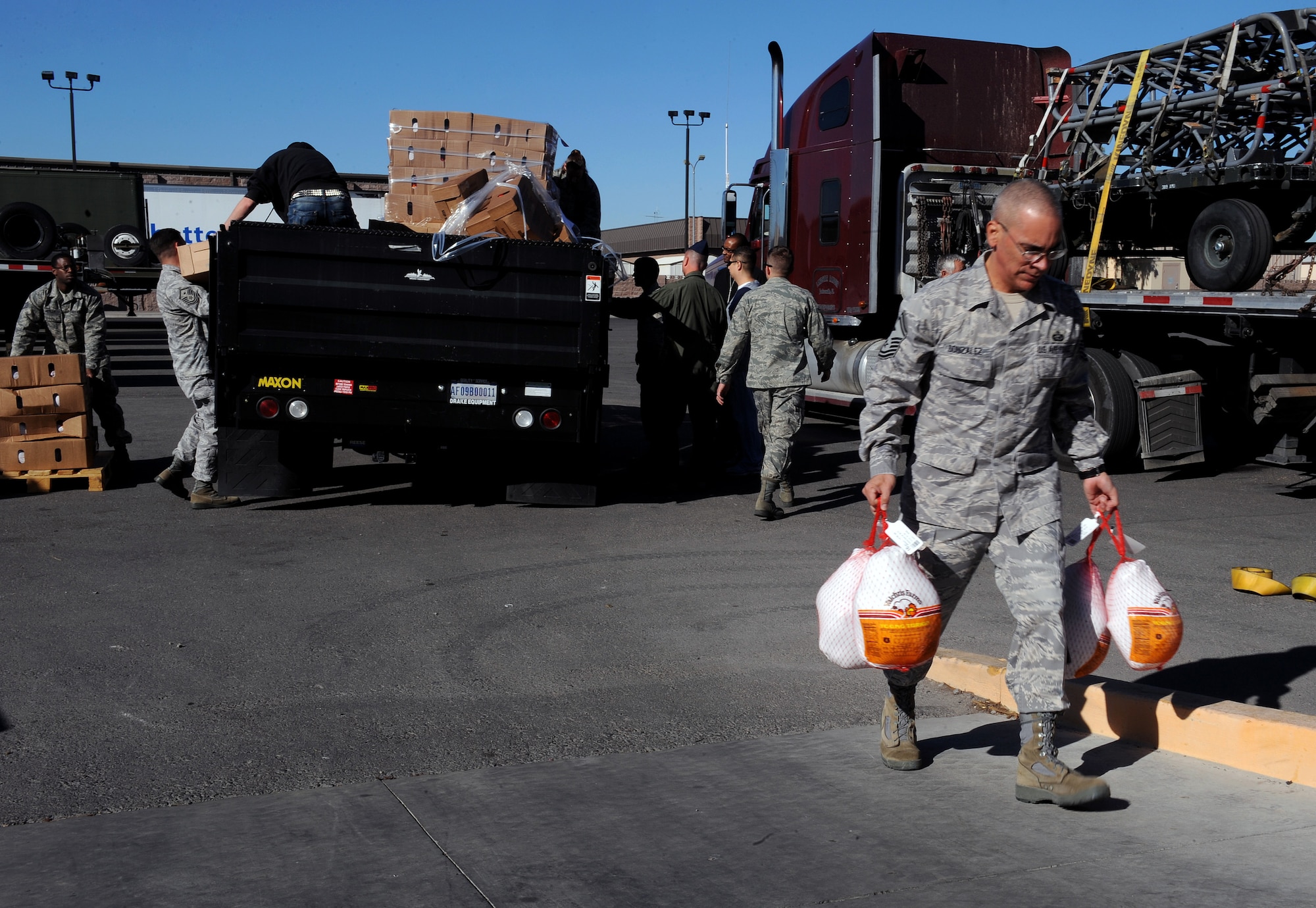 NELLIS AIR FORCE BASE, Nev. -- Senior Master Sgt. Jose Gonzalez, first sergeant with the 820th RED HORSE Squadron, carries turkey's from a loading truck during Operation Warmheart, Nov. 12. Nellis Airmen volunteered Friday morning to help create packages, and fill them with Thanksgiving meal items, so they can be delivered to homes and work centers. (U.S. Air Force photo by Senior Airman Brett Clashman)(Released)
