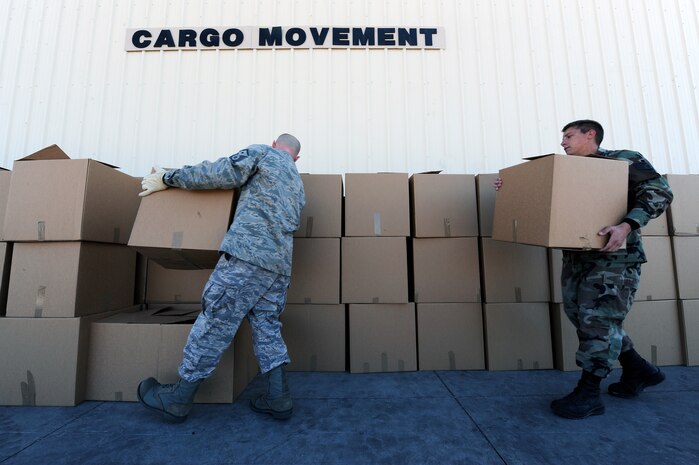 NELLIS AIR FORCE BASE, Nev. -- Master Sgt. Robert Workman, first sergeant with the U.S. Air Force Weapons School, and Staff Sgt. Jeremy Banfield, vehicle operations specialist with the 99th Logistics Readiness Squadron, move Thanksgiving gift baskets outside to be prepared for delivery during Operation Warmheart, Nov. 12. Nellis Airmen volunteered Friday morning to help create packages, and fill them with Thanksgiving meal items, so they can be delivered to homes and work centers. (U.S. Air Force photo by Senior Airman Brett Clashman)(Released)