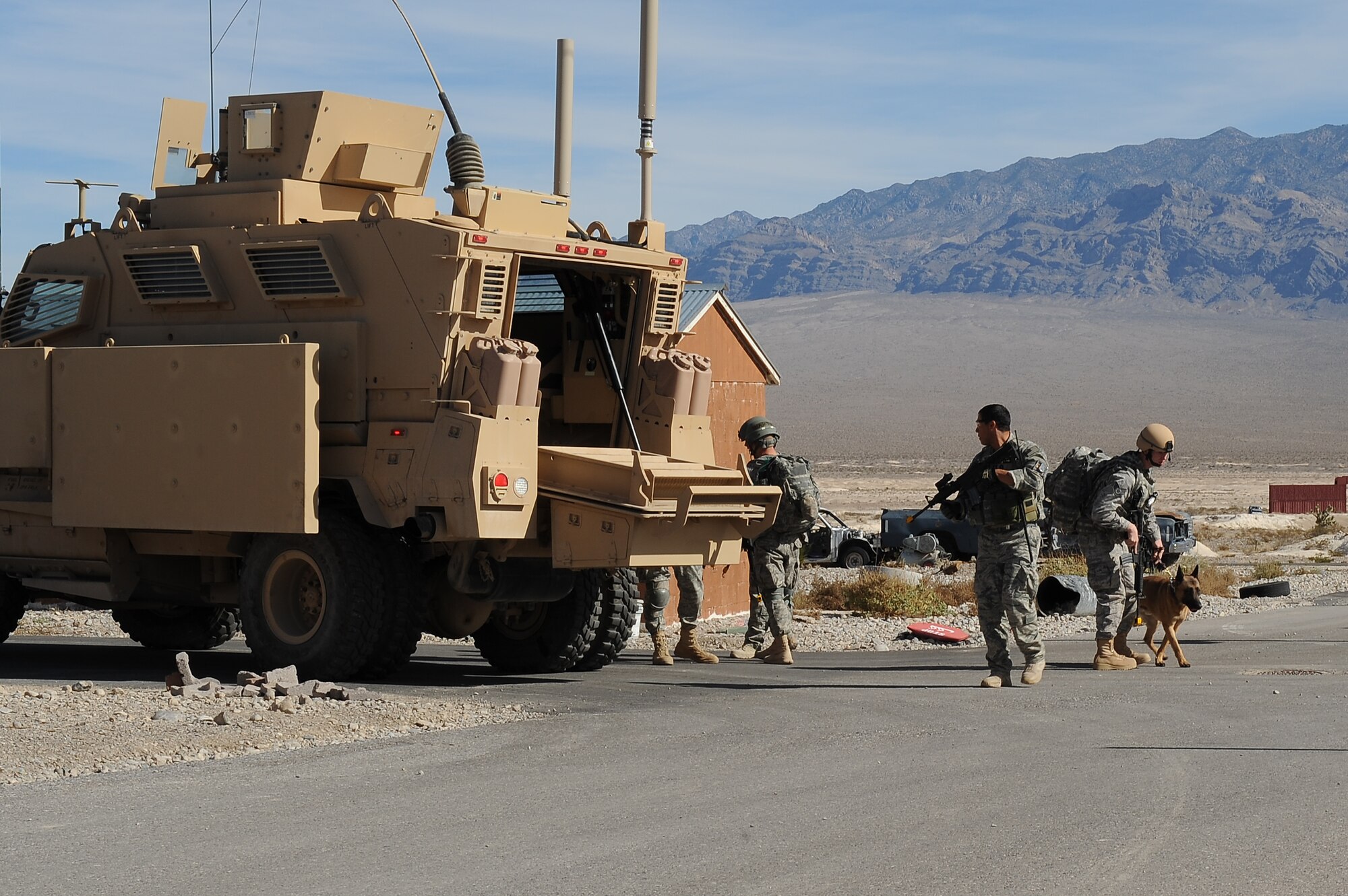 NEVEDA TEST AND TRAINING RANGE -- Security forces Airmen and their military working dogs secure the area after exiting a Mine Resistant Ambush Protected vehicle during a training exercise Oct. 29. The training is part of a new Nellis Air Force Base program created to condense the current 80 day training curriculum for handlers and military working dogs. (U.S. Air Force photo by Airman 1st Class Daniel Hughes/Released)
