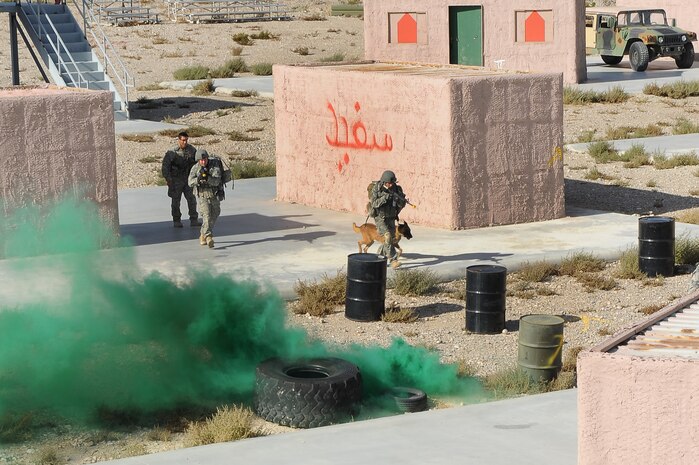 NEVEDA TEST AND TRAINING RANGE -- Security forces Airmen and their military working dogs cross an open court yard during a training exercise Oct. 29. The training exercise is part of a new Nellis Air Force Base program created to condense the current 80 day training curriculum for handlers and military working dogs. (U.S. Air Force photo by Airman 1st Class Daniel Hughes/Released)
