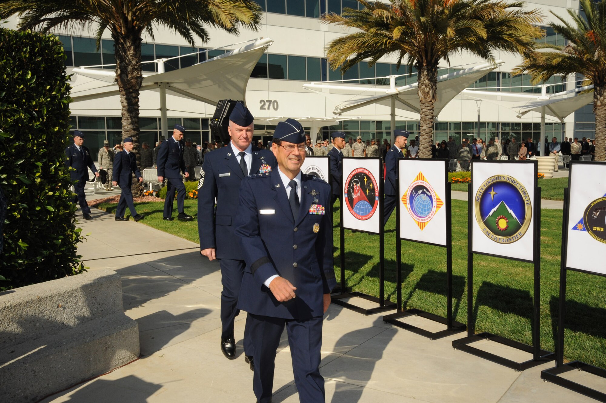 Lt. Gen. Tom Sheridan, SMC commander, walks past new unit patches at the transition ceremony changing SMC’s wings and groups to directorates and divisions, Nov. 10. The move was made as part of the Air Force’s continued efforts to improve acquisition, better structure programs for success, and the Air Force Chief of Staff’s recently established threshold manning requirements for all Air Force units.  (Photo by Lou Hernandez) 