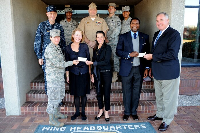 Col. Martha  Meeker, left, joined by members of the Joint Base Charleston Military Ball Committee, presents a check from the committee to Eleanor Smythe and Alix Tea, while Rear Adm. (Ret.) Robert Besal, right, presents a check to D. Jermoine Husser at JB CHS-Air Base, S.C., Nov. 12, 2010. The funds were donated on behalf of the committee to the Lowcountry Food Bank and Camp Happy Days, a comprehensive, year-round support system for children diagnosed with cancer and their families. Colonel Meeker is the 628th Air Base Wing commander, Admiral Besal is with the Navy League Charleston, Ms. Smythe and Ms. Tea work with Camp Happy Days, and Mr. Husser is with the Lowcountry Food Bank. (U.S. Air Force Photo/James M. Bowman)