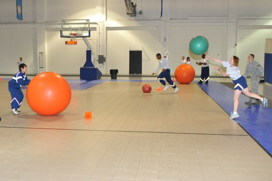 OFFUTT AIR FORCE BASE, Neb. - Senior Master Sgt. Jayne Cooper fires a ball at Senior Airman Jing Shi who takes cover behind a large ball during the mega ball challange Nov. 12 in the Offutt Field House. Airmen with the 55th Wing took part in various events and briefings around the base during Wingman Day 2010 to promote teamwork and educate Airmen on things such as suicide prevention and the dangers of drinking and driving. U.S. Air Force photo by Jeff W. Gates. 
