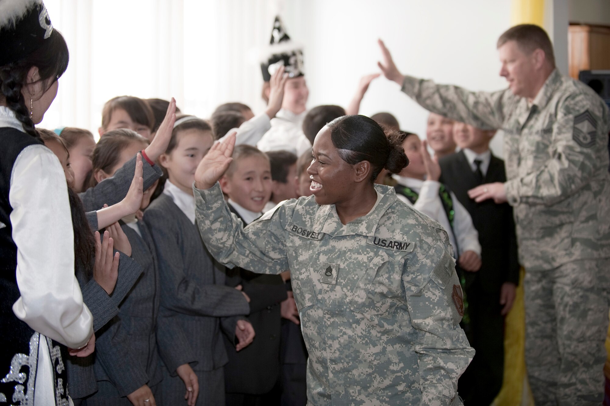 Army Staff Sgt. Zenia Boswell and Chief Master Sgt. Leland Becker high-five Chuiskaya Region Boarding School-Gymnasium students Nov. 11, 2010, at their school in Koi Tash, Kyrgyzstan. Kyrgyz and U.S. military members gave students coats, blankets and hats as part of Operation Warm and Dry II. Sergeant Boswell is assigned to the U.S. Embassy, and Chief Becker is assigned to the Transit Center at Manas. (U.S. Air Force photo/Tech. Sgt. Jennifer Buzanowski)