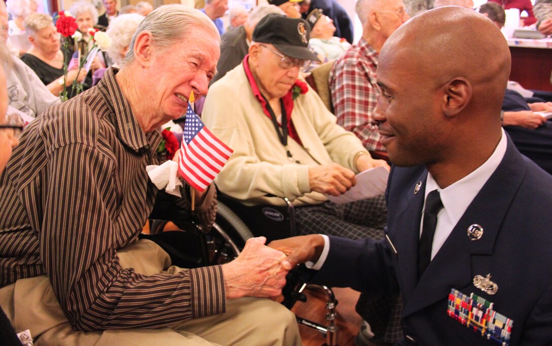 Tech. Sgt. Thomas Metcalf, a members of the 310th Mission Support Group, talks to Don Ness while handing out flags at the Veterans Day ceremony in Aurora, Colo. The 310th Space Wing teamed up with the Denver Hospice to honor local veterans during a Veterans Day ceremony at the Veterans Nursing Home at Fitzsimons on Nov. 11. (U.S. Air Force photo/Tech. Sgt. Scott P. Farley)