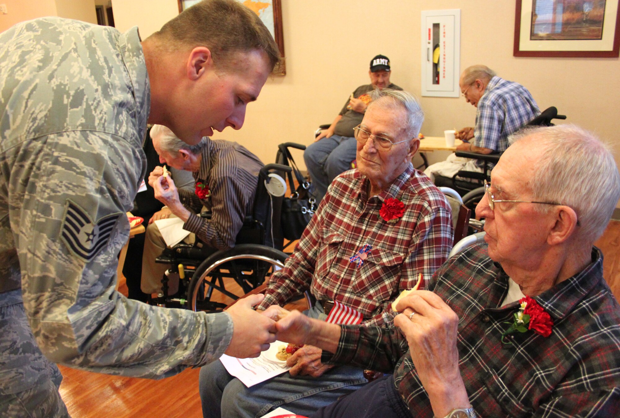 Tech. Sgt. Joseph Schwartz, a 310th Security Forces member, learns a new hand shake from Warren "Hutch" Hutchings (right), while Joseph Griggs watches at the veterans nursing home in Aurora, Colo. The 310th Space Wing teamed up with the Denver Hospice to honor local veterans during a Veterans Day ceremony at the Veterans Nursing Home at Fitzsimons on Nov. 11. (U.S. Air Force photo/Tech. Sgt. Scott P. Farley)