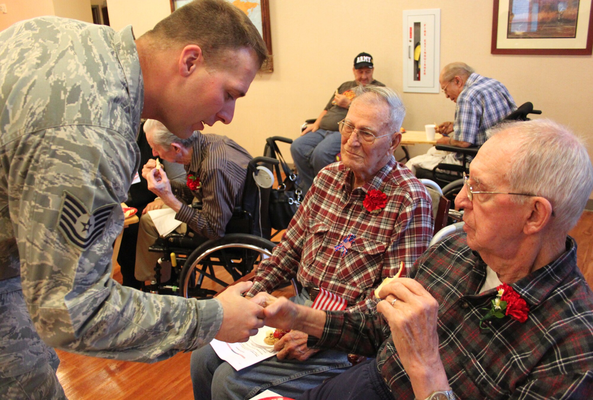 Tech. Sgt. Joseph Schwartz, a 310th Security Forces member, learns a new hand shake from Warren "Hutch" Hutchings (right), while Joseph Griggs watches at the veterans nursing home in Aurora, Colo. The 310th Space Wing teamed up with the Denver Hospice to honor local veterans during a Veterans Day ceremony at the Veterans Nursing Home at Fitzsimons on Nov. 11. (U.S. Air Force photo/Tech. Sgt. Scott P. Farley)