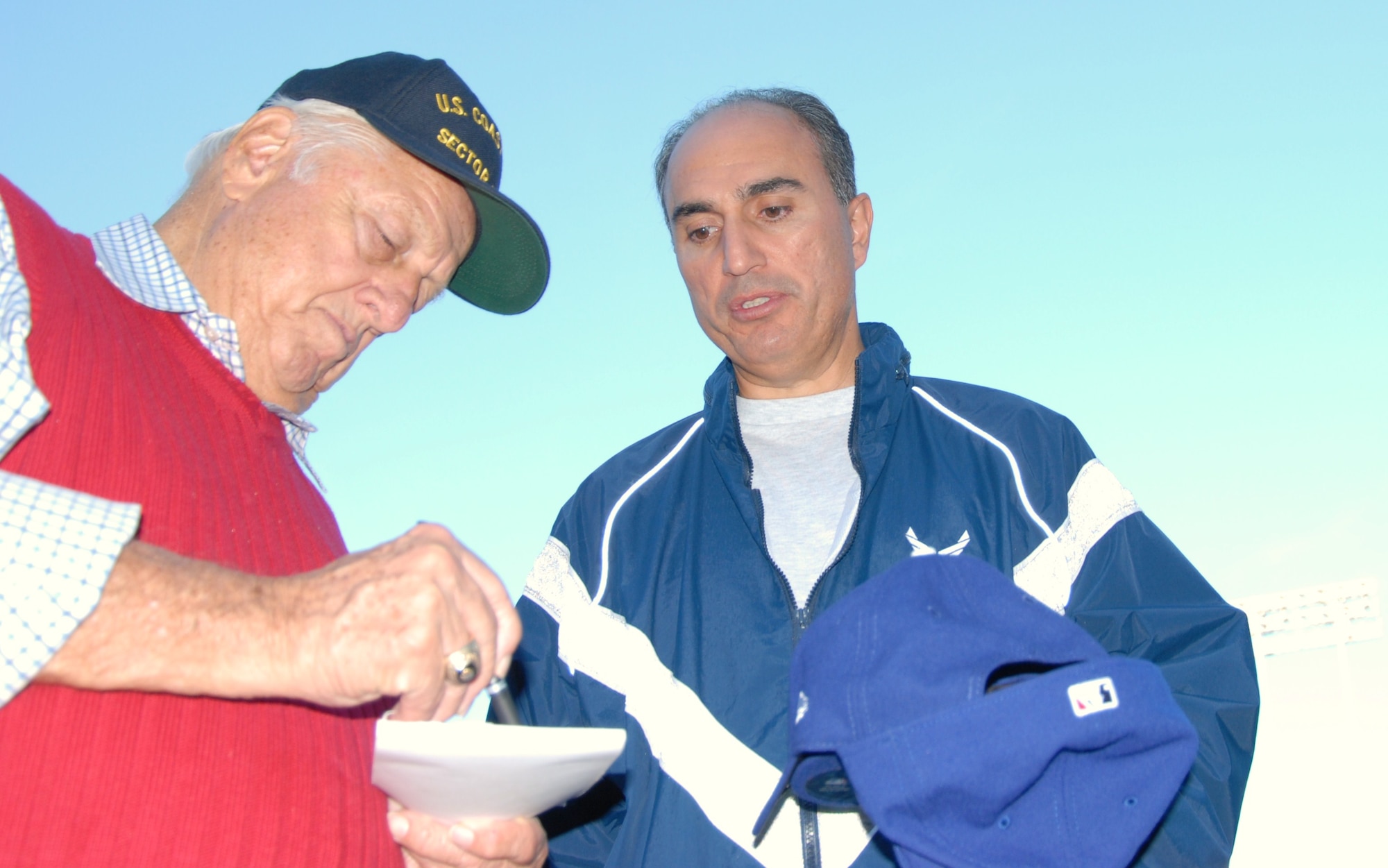 Col. Joe Torres, 95th Air Base Wing vice commander, looks on as Hall of Fame manager Tommy Lasorda signs an autograph. The Los Angeles Dodgers organization, along with Mr.Lasorda and other Dodger alumni, hosted "Veterans Day Batting Practice at Dodger Stadium" for local-area veterans and their families. (Air Force photo by Kate Blais)