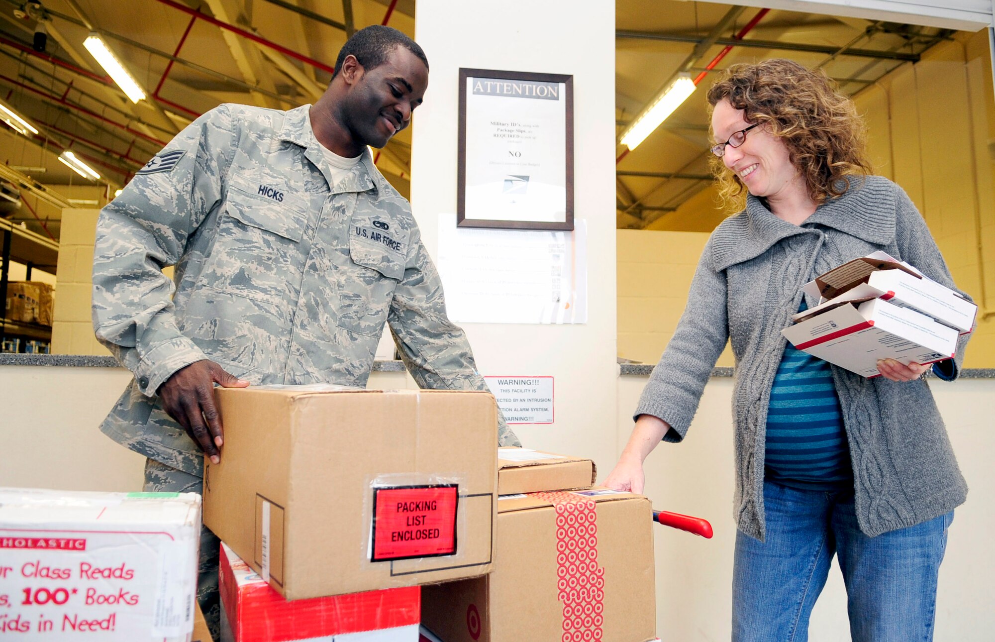 RAF MILDENHALL, England -- Staff Sgt. Dustin Hicks, 100th Communications Squadron postal specialist, hands Angela Leeds, a Team Mildenhall spouse, a cart of her packages at the base post office Nov. 15, 2010. The post office provides carts to people who have multiple packages and assistance to anyone who may need help transporting and loading their parcels into their vehicles. (U.S. Air Force photo/Senior Airman Ethan Morgan)