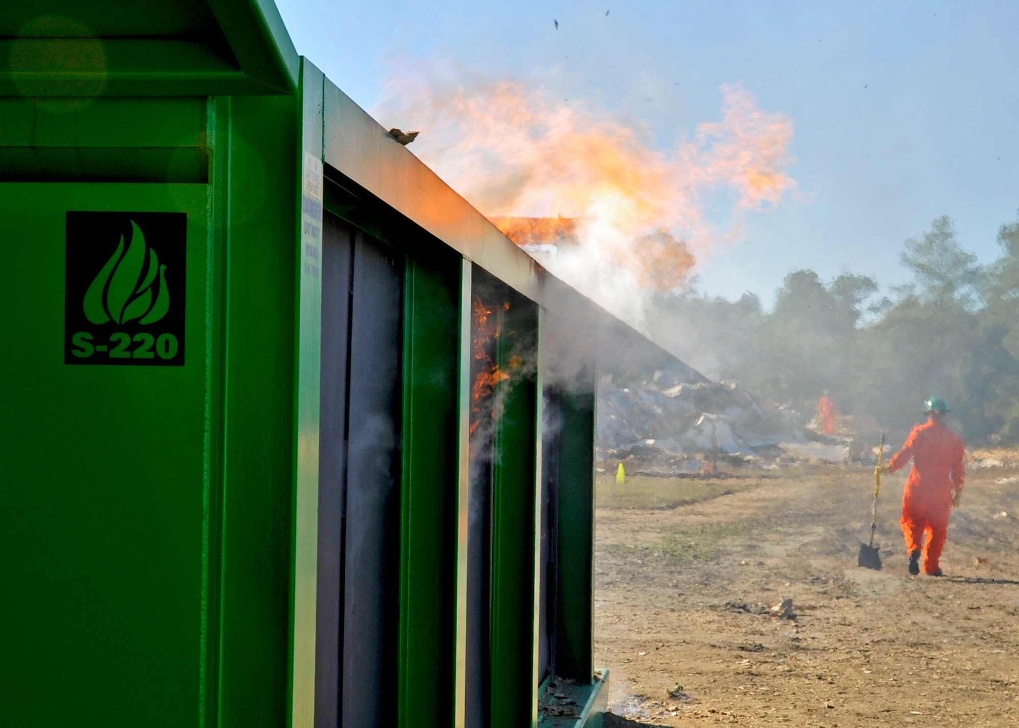 Fire spills over the side of the 46th Test Wing’s new air curtain incinerator on a gusty day out on Eglin’s range.  The incinerator or air burner helps the wing get rid of test materials used to detect direction and velocity of bomb explosion fragments.  The burner, which would consume massive amounts of the wood waste quickly and minimize the amount of pollutants released.  (U.S. Air Force photo/ Samuel King Jr.)