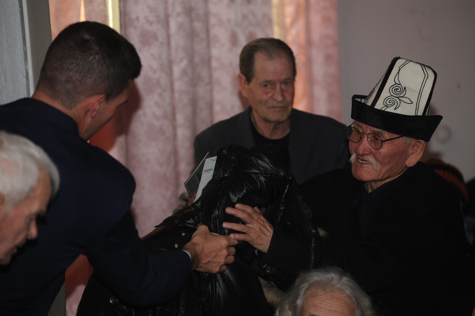 BISHKEK, Kyrgyzstan -  Col. Dwight Sones, 376th Air Expeditionary Wing commander, gives a coat to an elderly gentleman at a retirement home in Bishkek Nov. 13.  The Transit Center at Manas donated 226 cold weather coats in support of Operation Warm & Dry II.  (U.S. Air Force photo/Staff Sgt. Nathan Bevier)