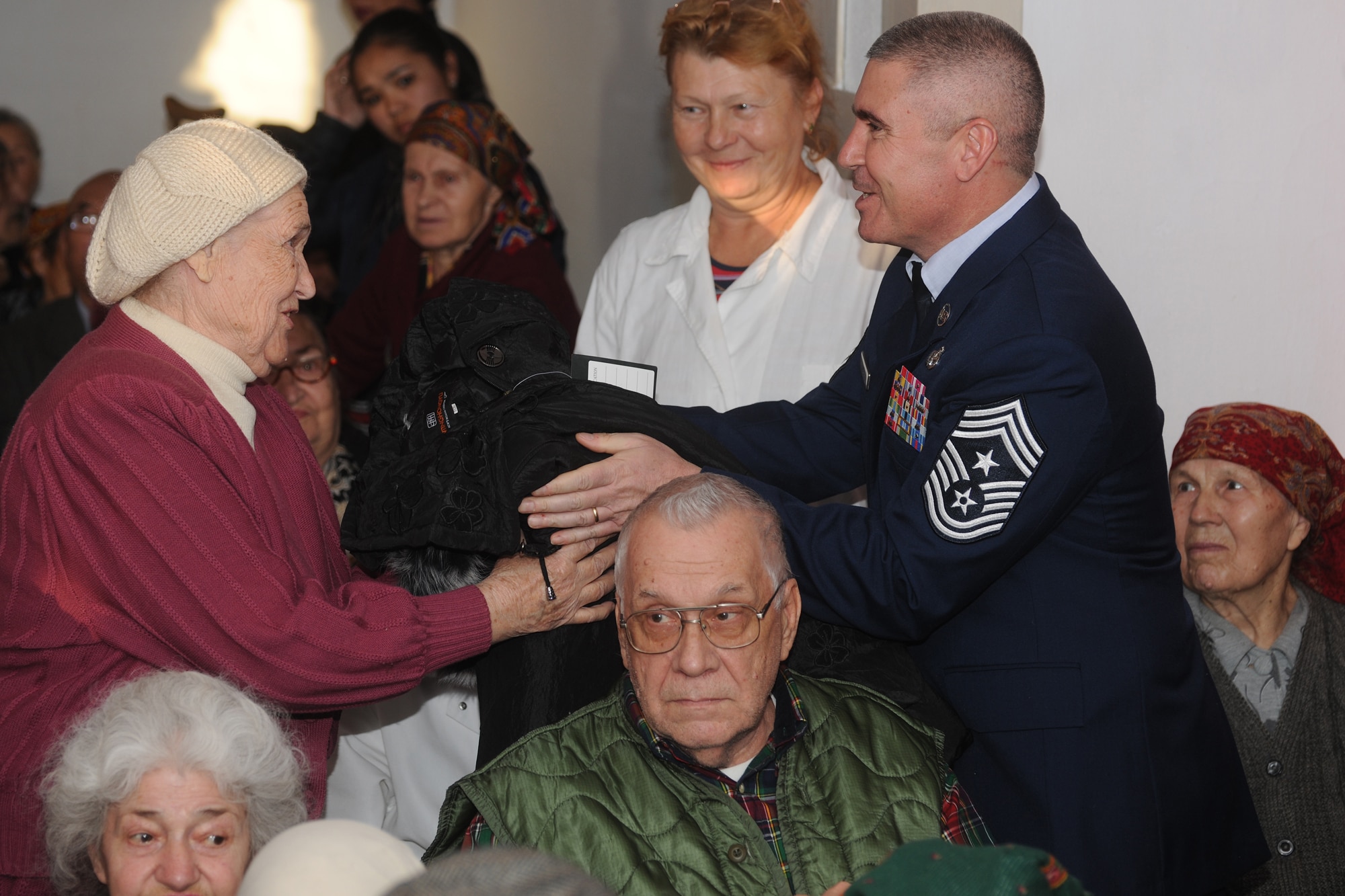 BISHKEK, Kyrgyzstan -  Chief Master Sgt. James Lucas, 376th Air Expeditionary Wing command chief, gives a coat to an elderly lady at a retirement home in Bishkek Nov. 13.  The Transit Center at Manas donated 226 cold weather coats in support of Operation Warm & Dry II.  (U.S. Air Force photo/Staff Sgt. Nathan Bevier)