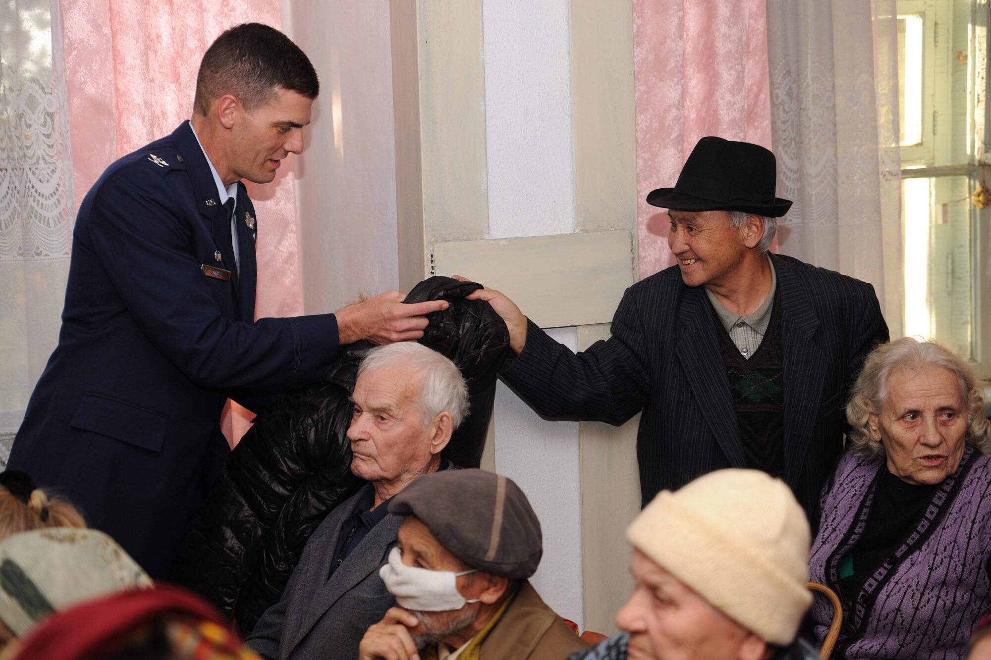 BISHKEK, Kyrgyzstan -  Col. Dwight Sones, 376th Air Expeditionary Wing commander, gives a coat to an elderly gentleman at a retirement home in Bishkek Nov. 13.  The Transit Center at Manas donated 226 cold weather coats in support of Operation Warm & Dry II.  (U.S. Air Force photo/Staff Sgt. Nathan Bevier)