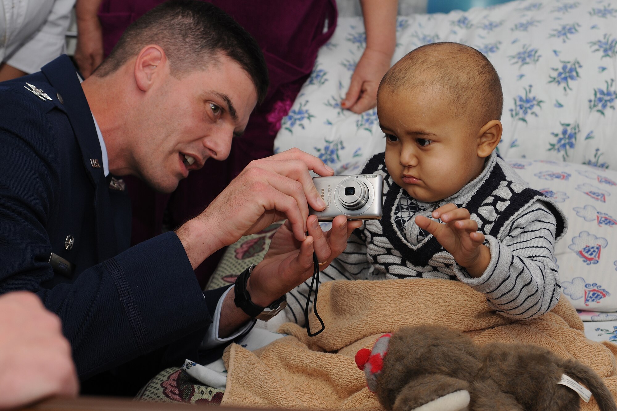 BISHKEK, Kyrgyzstan -  Col. Dwight Sones, 376th Air Expeditionary Wing commander, shows a child how to take a picture at the Children's Cancer Center in Bishkek Nov. 13.  Members from the Transit Center at Manas visited the children as part of a team to assess the needs of the facility.  (U.S. Air Force photo/Staff Sgt. Nathan Bevier)