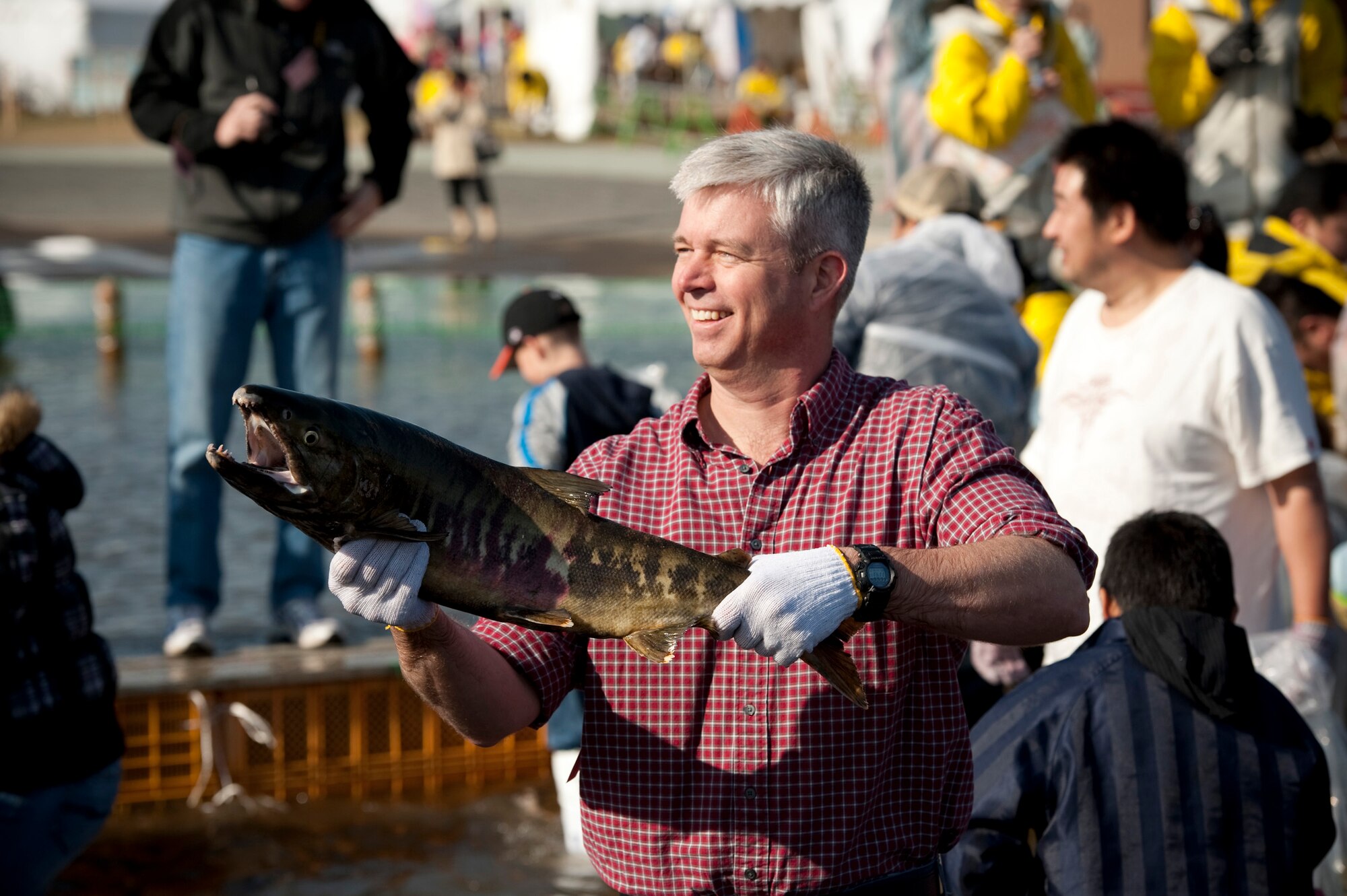 U.S. Air Force Col. Van Wimmer, 35th Fighter Wing vice commander, holds up his catch at Salmon Park, Oirase, Japan, during the Oirase Salmon Catching Festival. After catching a salmon, festival staff members provided participants with plastic bags to help prevent the fish from regaining their freedom. (U.S. Air Force photo by Staff Sgt. Samuel Morse/Released)