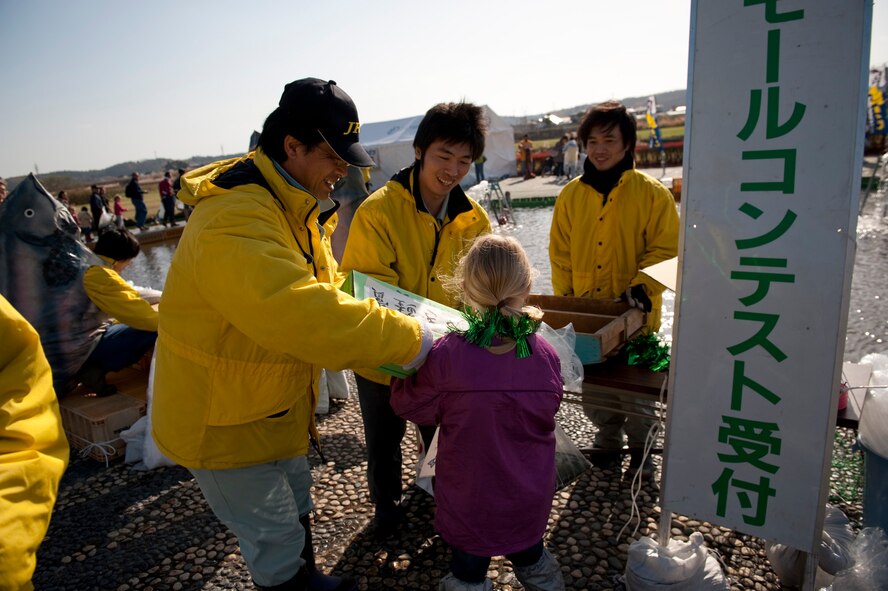 Lindsay-Clair Light receives a prize from Oirase Salmon Catching Festival staff members at Salmon Park, Oirase, Japan, during the festival, Nov. 13, 2010. Prizes were given to participants who caught the largest or smallest salmon, as well as any that had a pink ribbon tied around its tail. (U.S. Air Force photo by Staff Sgt. Samuel Morse/Released)