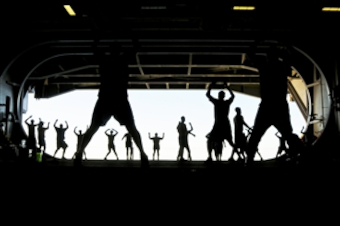 U.S. Navy sailors from the engineering repair division perform jumping jacks during group physical training in the hangar bay of the aircraft carrier USS Ronald Reagan in the Pacific Ocean, Nov. 12, 2010. The Ronald Reagan is completing a training exercise to prepare for deployment.