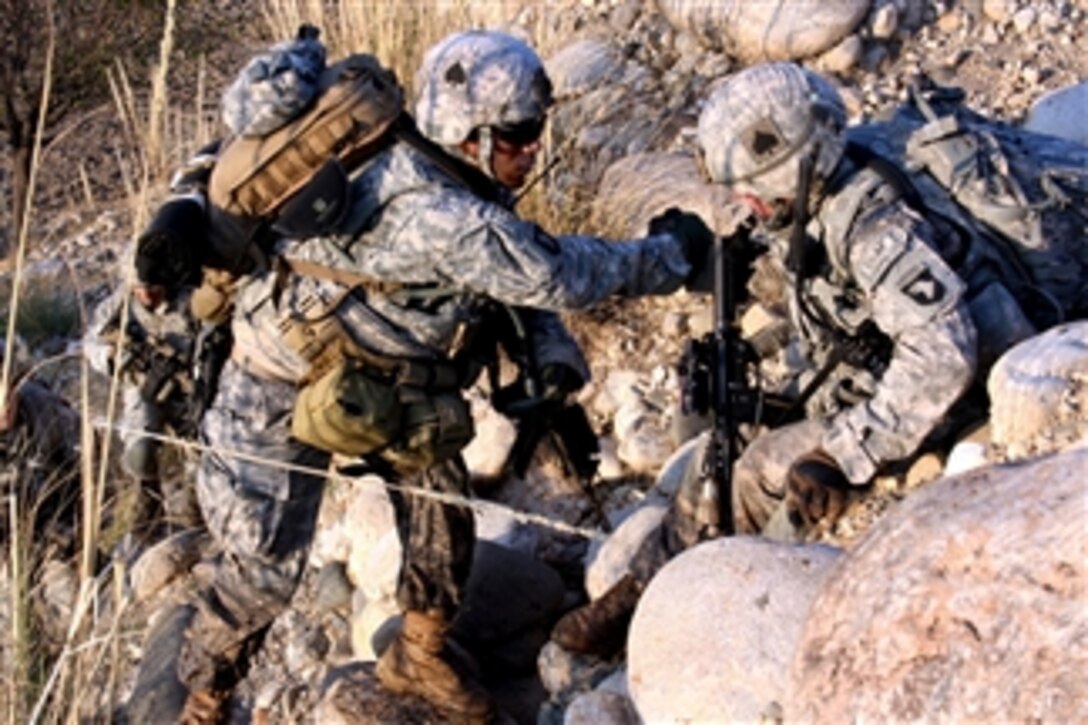 U.S. Army Sgt. James Small (right) helps Spc. Andreas Plaza up a mountainside in the Towr Gahr Pass, Nangarhar province, Afghanistan, on Nov. 6, 2010.  Small and Plaza are assigned to 1st Squadron, 61st Cavalry Regiment.  