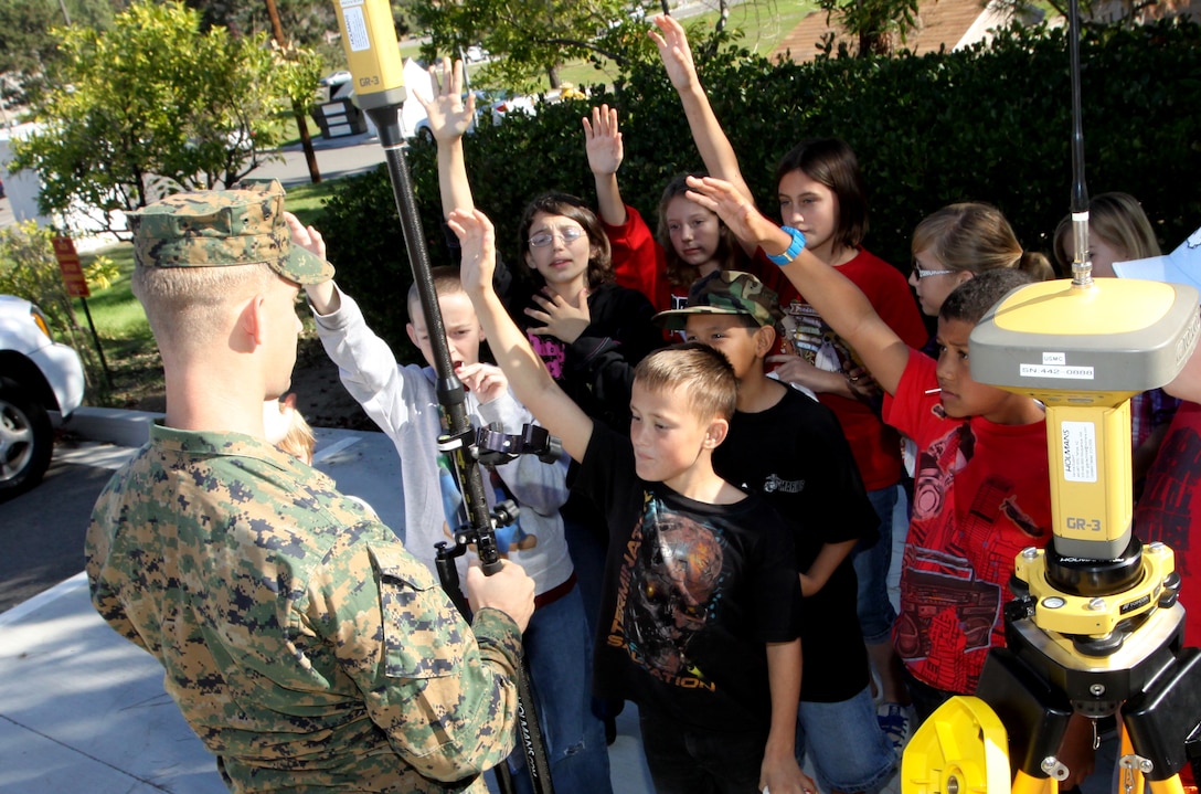 Children from Mary Fay Pendleton Elementary School raise their hands for a chance to operate an advanced measure device during the fourth annual Geospatial Information Systems Day, at building 1160 Nov. 17. More than 100 students from the base’s school attended the event for a better understanding of what GIS is, through visual displays, informational booths and by receiving first-hand information from the base’s GIS experts.