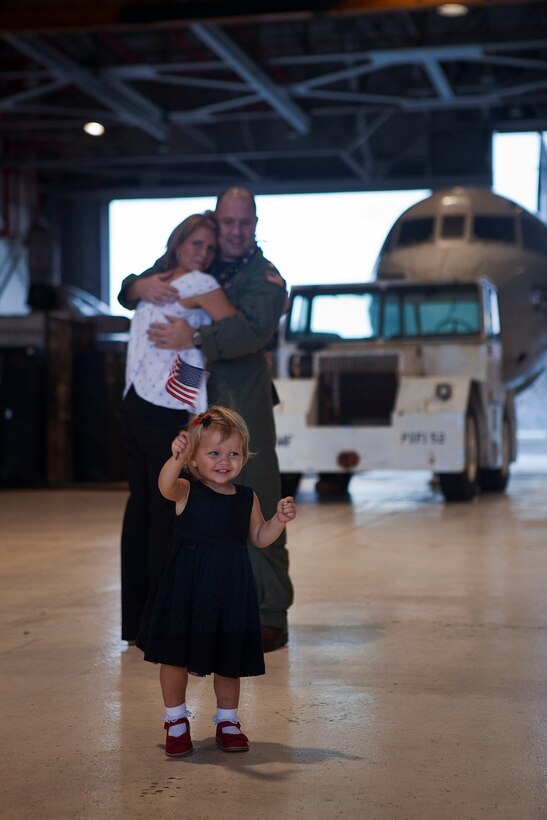 Lt. Cmdr. Alan Miller, training officer, Patrol Squadron 9, embraces his wife and watches as their daughter excitedly waves an American flag following Miller’s return to Marine Corps Air Station Kaneohe Bay, Hawaii, from a six-month deployment, Nov. 16, 2010. During the deployment, VP-9 detached throughout the Navy’s 5th and 7th Fleet areas of responsibility. A group of VP-9 P-3s supported 5th Fleet maritime operations in Operation Iraqi Freedom from Isa Air Base in Bahrain. From their hub at Kadena Air Base, the remaining portion of VP-9 detached throughout the 7th Fleet AOR, working with a variety of coalition partners including Guam, Indonesia, Malaysia, the Philippines, Singapore, South Korea and Thailand.