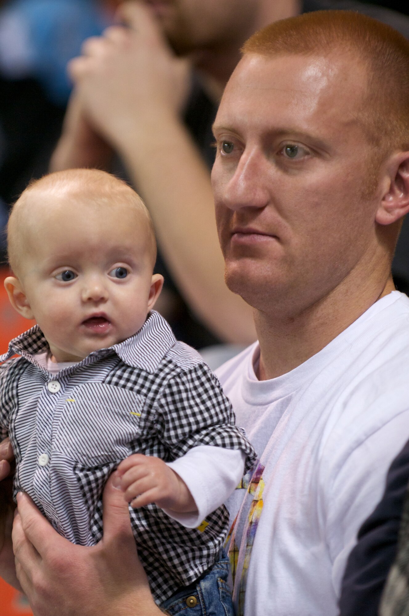 Air Force Staff Sgt. Tim Hessler, 703rd Aircraft Maintenance Squadron, holds  5-month-old son Briggs during a Nov. 13 Alaska Aces hockey team military appreciation game at the Sullivan Arena. (Photo by David Bedard/JBER PAO)
