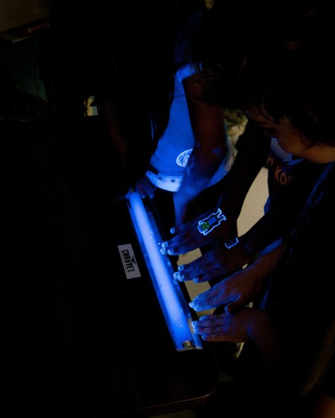 Osan American Elementary School students place their hands under an ultraviolet black light to check for any spots missed after washing during the “Teddy Bear Clinic.” (Courtesy photo)