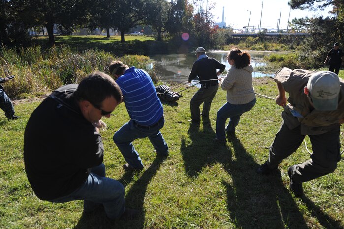 Employees from Gator Getters Consultants move Charlie the alligator from his home Nov. 17, 2010, Joint Base Charleston-Weapons Station S.C. Charlie is being temporarily moved from his home for pond cleaning, overflow structure improvements and increased pond depth of eight feet. There will also be two dens built in the pond so Charlie and the other alligators can hibernate. Gator Getters have more than 20 years of experience moving alligators like Charlie.(U.S. Air Force photo/James M. Bowman)