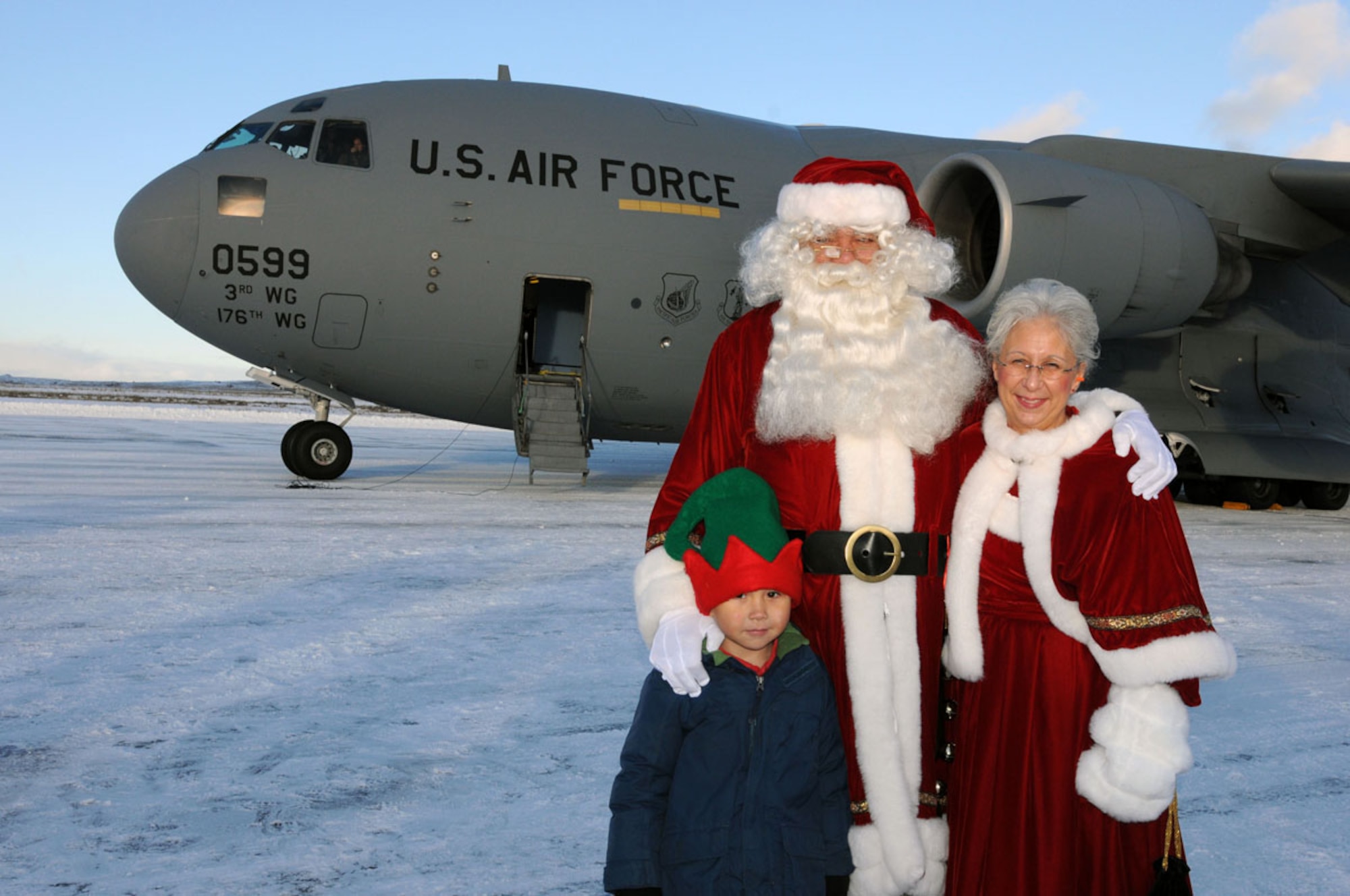 Santa, Mrs. Claus and 4-year-old Ethan Lestenkof-Mandregan pose in front of an Air Force C-17 Globemaster III at St. Paul after Santa lands and greets the community as part of the 54th Annual Operation Santa Claus Nov. 6. Ethan was the first child to run to Santa. (Alaska Army National Guard photo/Pfc. Karina Paraoan)