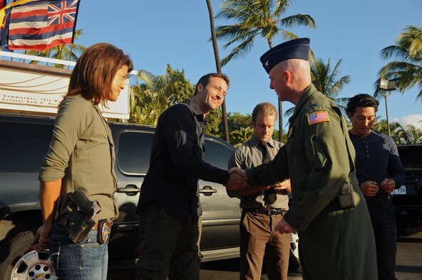 Col. Sam Barrett, 15th Wing commander, hands a coin to Hawaii Five-0 star Alex O'Loughlin during a break in the filming of a scene Nov. 11 at Joint Base Pearl Harbor Hickam. Colonel Barrett presented coins to the hit show's cast and crew. (U.S. Air Force Photo/Master Sgt. Jeffrey Allen) 