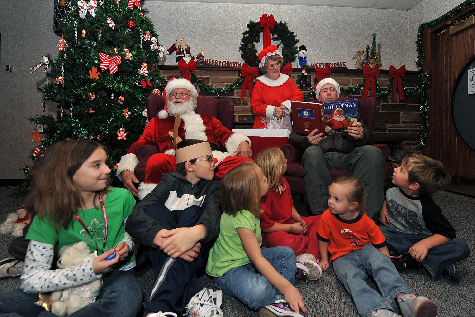 OFFUTT AIR FORCE BASE, Neb. -- Children listen to Brig. Gen. John N.T. Shanahan, 55th Wing commander, as he reads them a Christmas story during holiday connections in the Community Center here Nov. 16. More than 100 Team Offutt families attended and made gifts, cards and video messages for their loved ones who will be away from home this holiday season. The annual event, established in 2000, provides a fun environment  for families to come together and share a little joy. U.S. Air Force photo by Charles Haymond