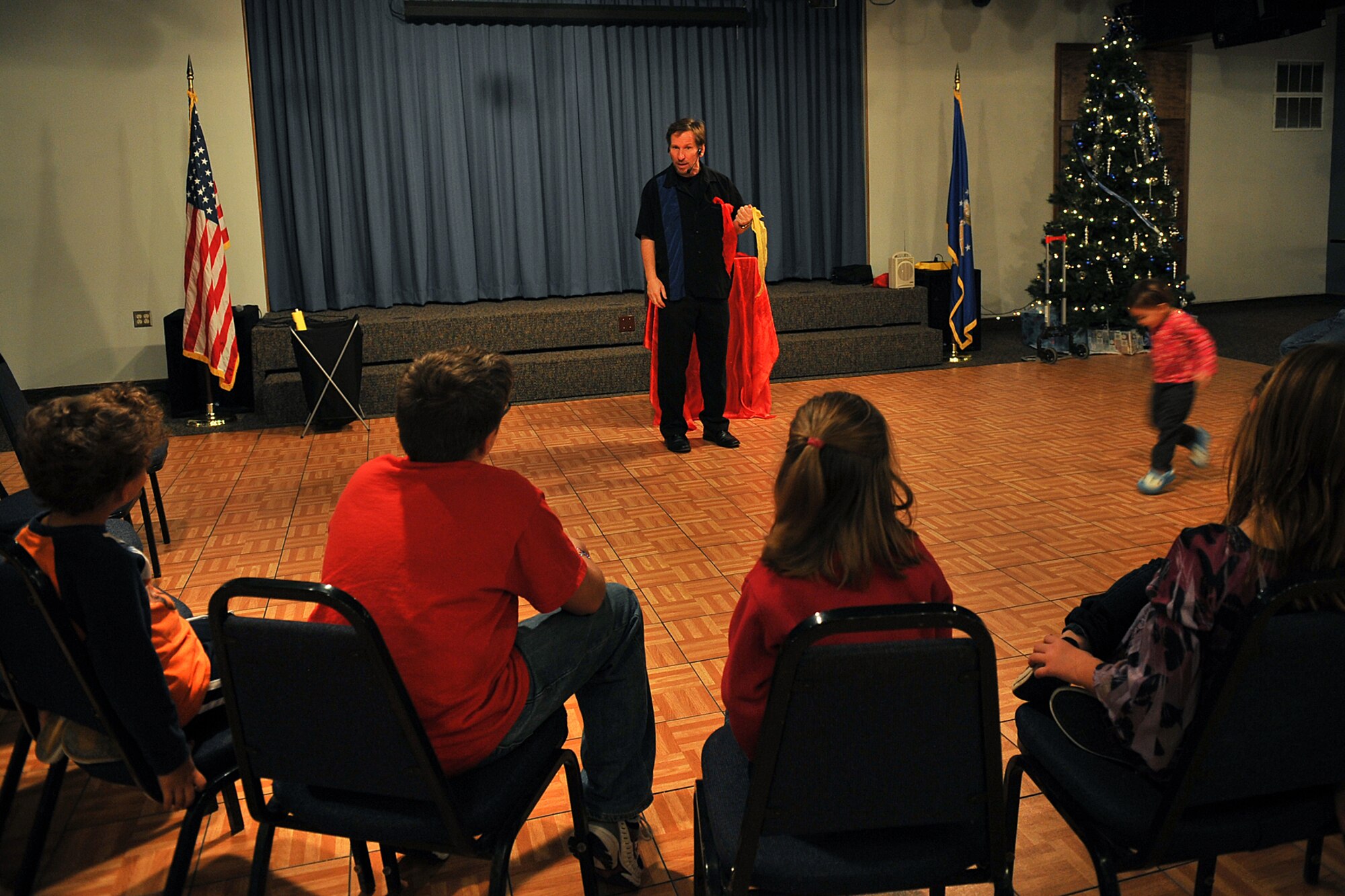 OFFUTT AIR FORCE BASE, Neb. -- Jeff Quinn, a local magician, entertains the crowd during holiday connections in the Community Center here Nov. 16. More than 100 Team Offutt families attended and made gifts, cards and video messages for their loved ones who will be away from home this holiday season. The annual event, established in 2000, provides a fun environment  for families to come together and share a little joy.
U.S. Air Force Photo by Charles Haymond